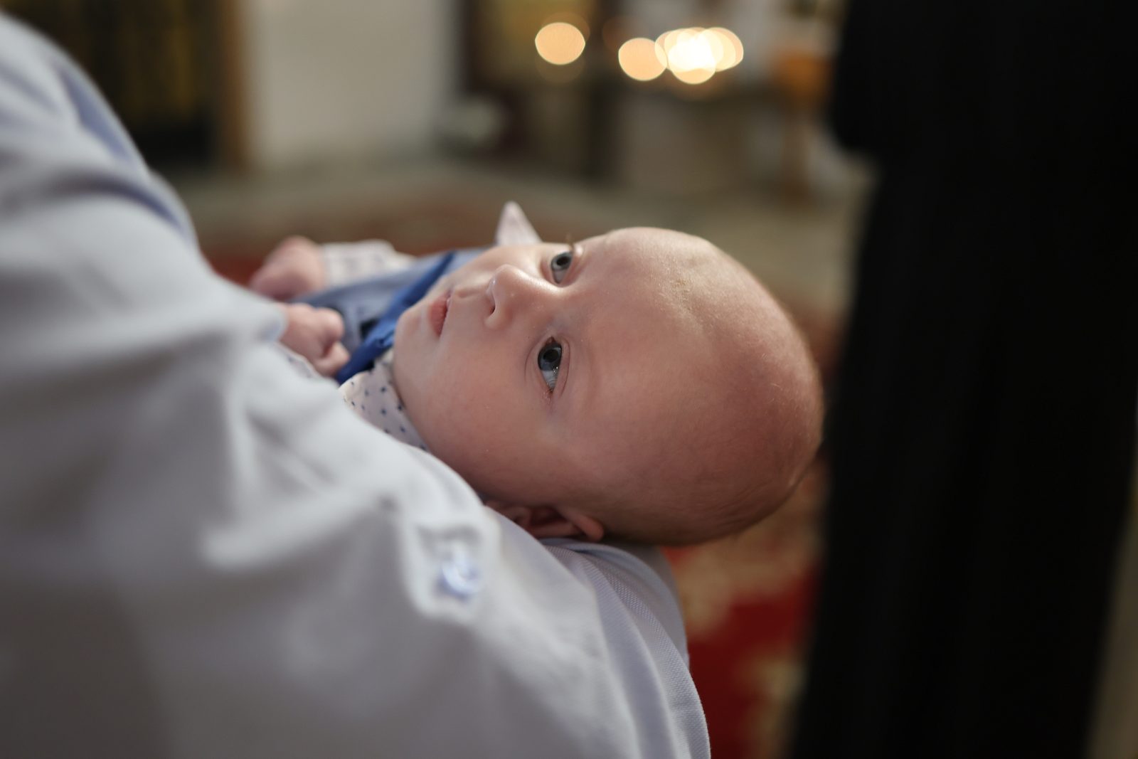 Infant held by an adult during the baptism ceremony