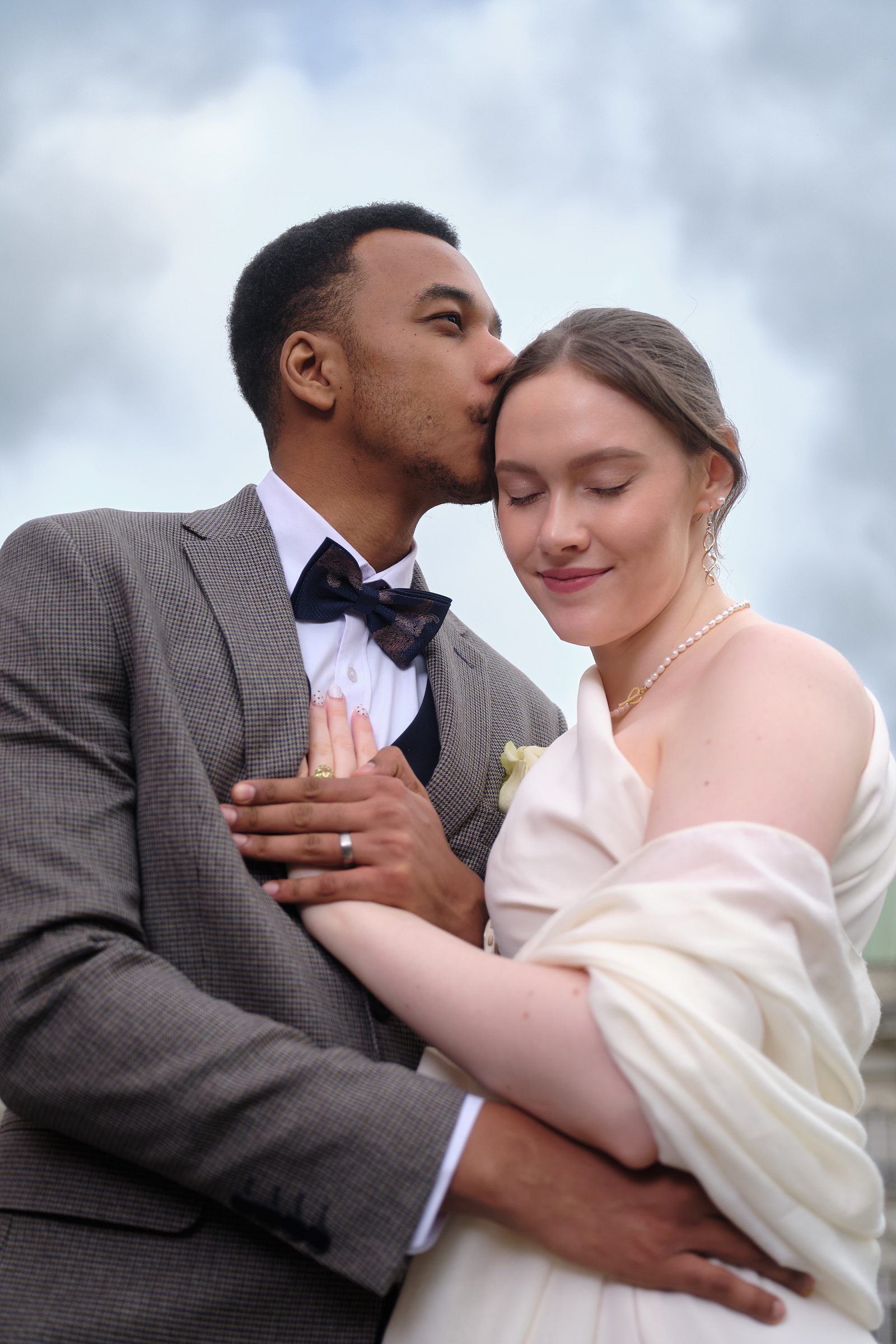 Close wedding portrait of the groom embracing the bride.