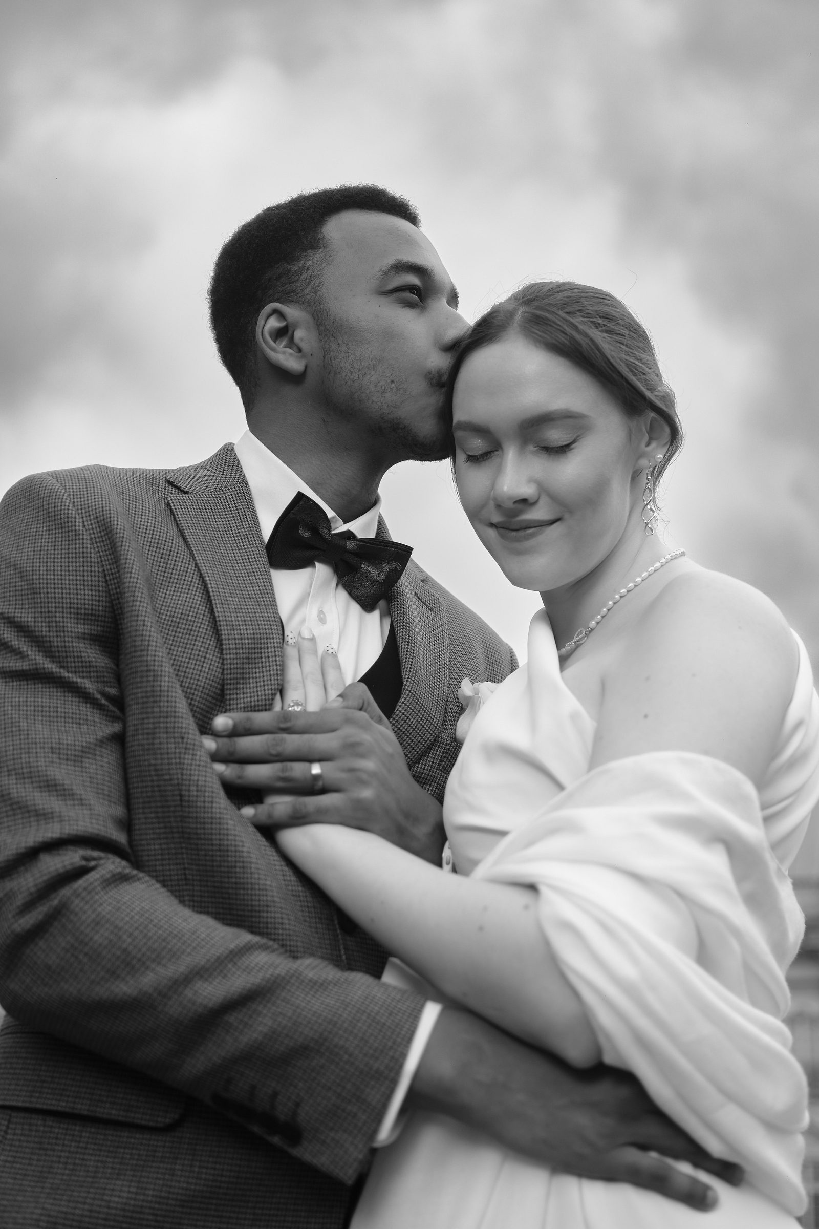 Black-and-white wedding portrait of the bride and groom embracing.