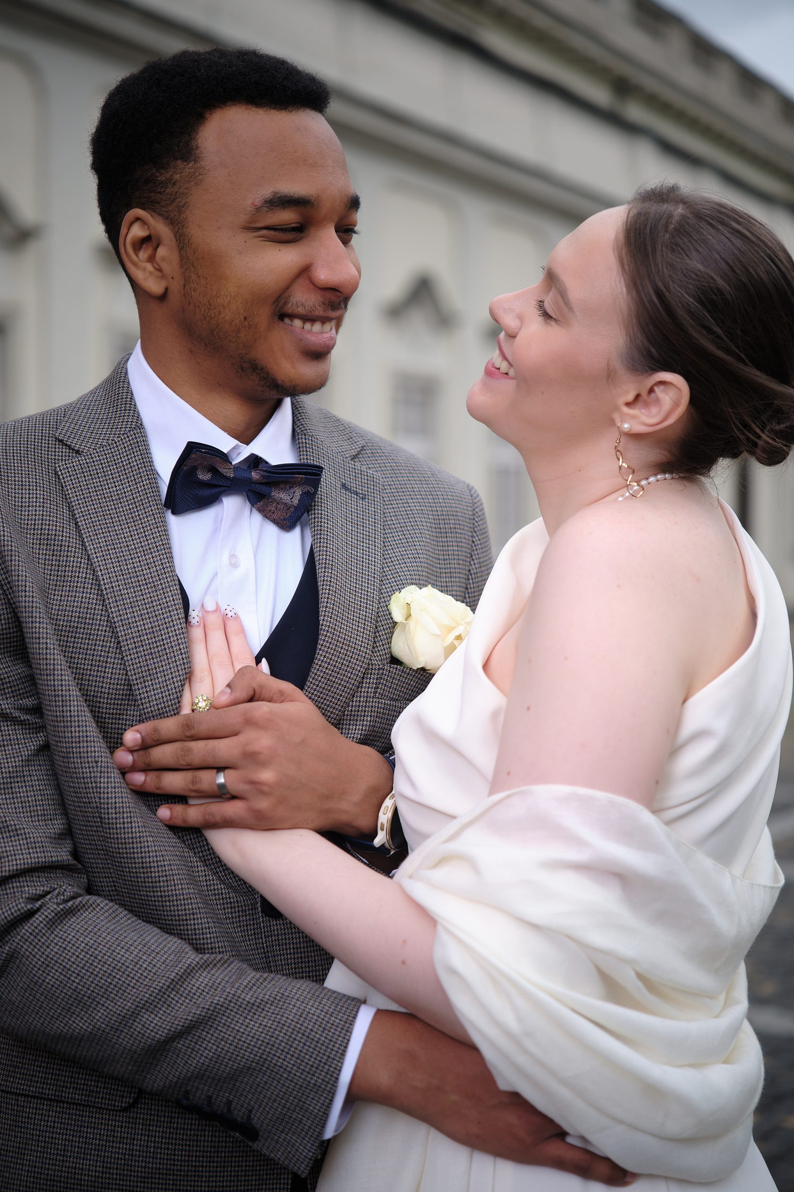 Close portrait of the groom smiling at the bride as she holds her bouquet.