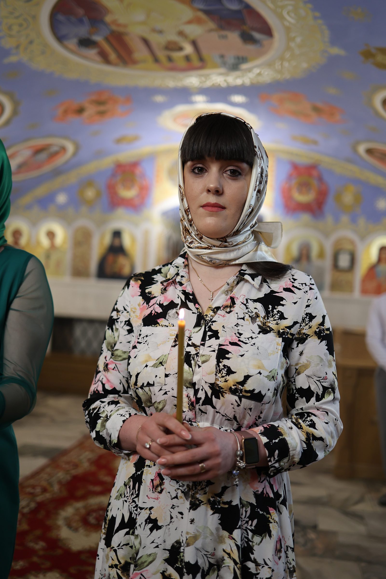 Woman holding a lit candle in church during baptism