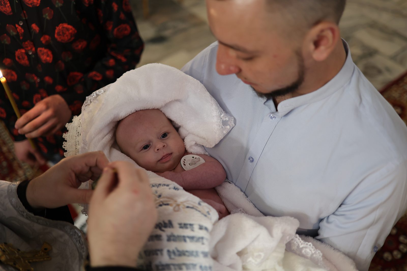 Infant in baptism clothing held by a man