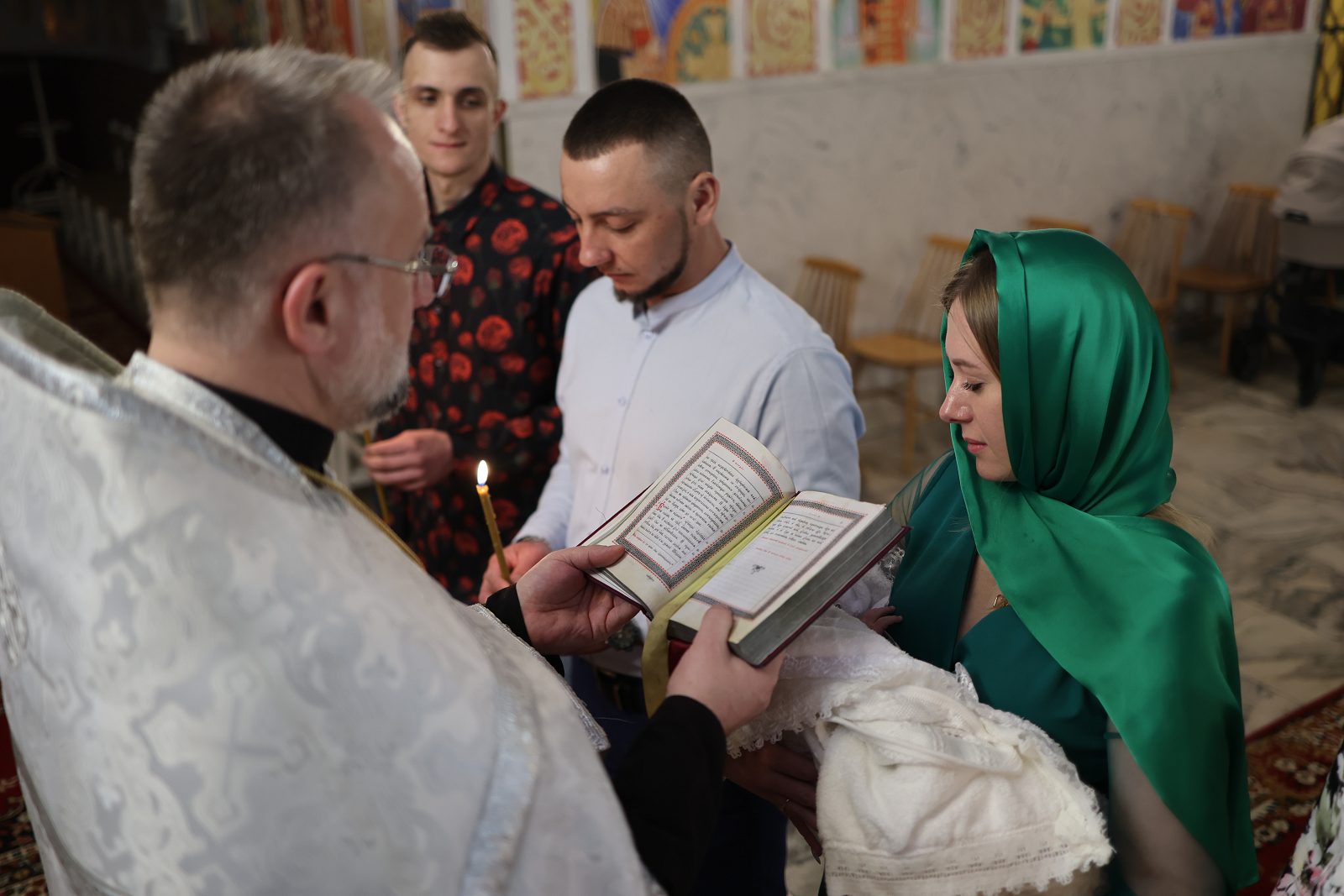 Priest reading a prayer to the family holding candles