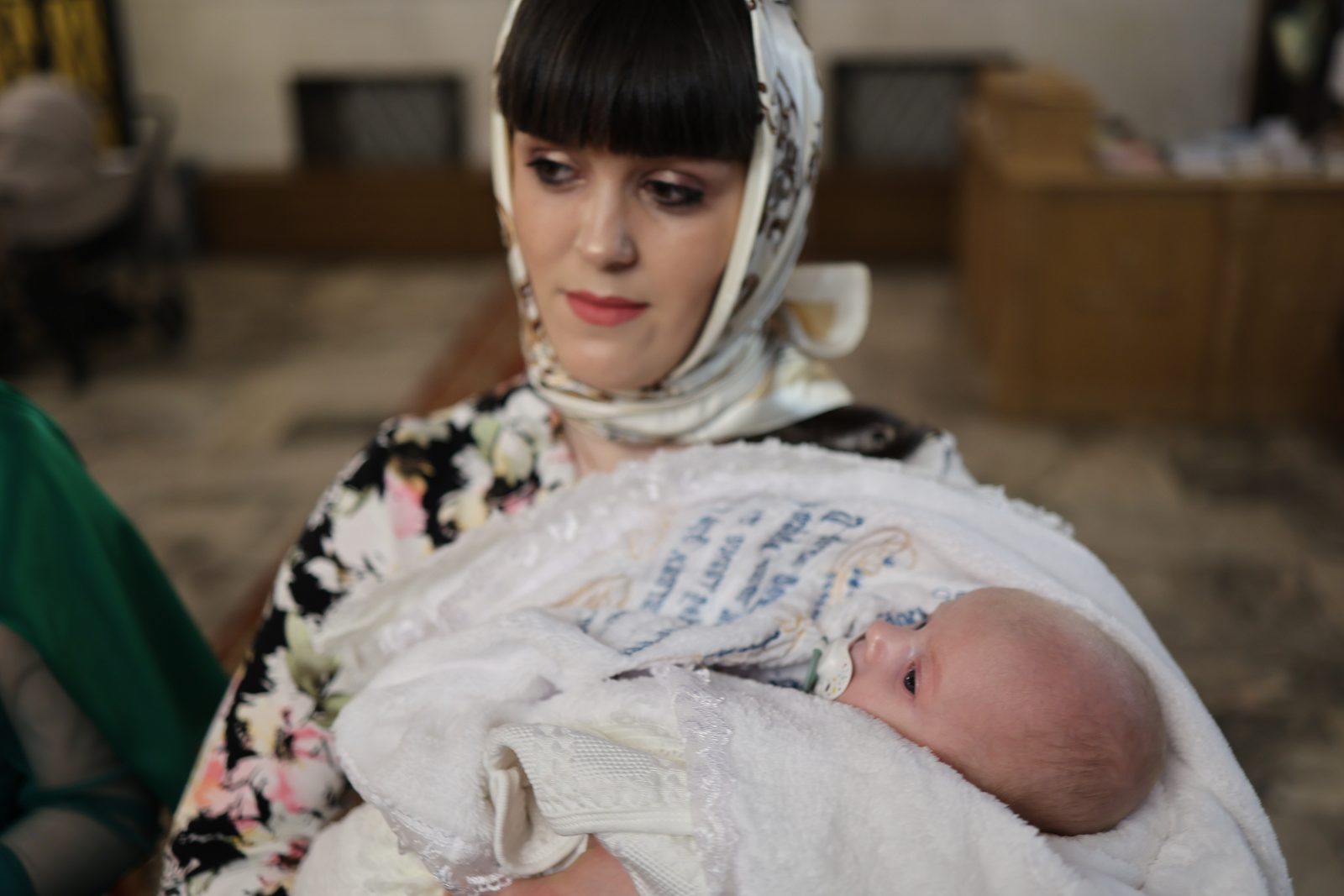 Woman holding an infant in baptism clothing