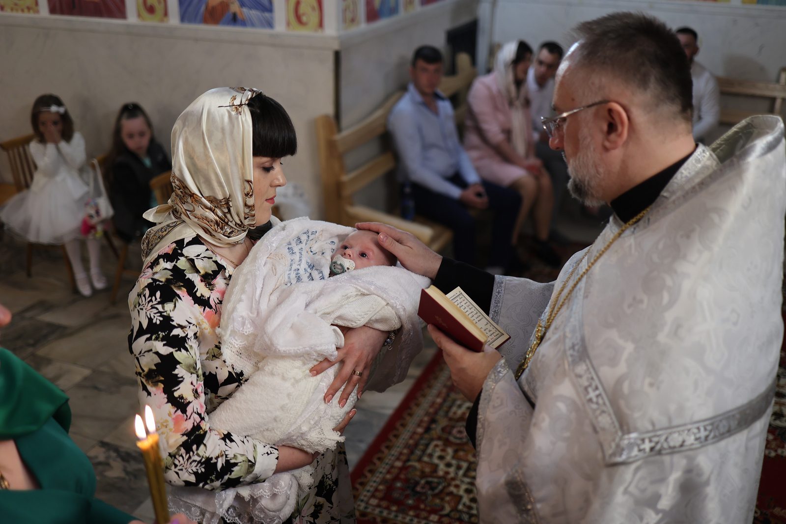 Priest performing a rite over an infant in white clothing