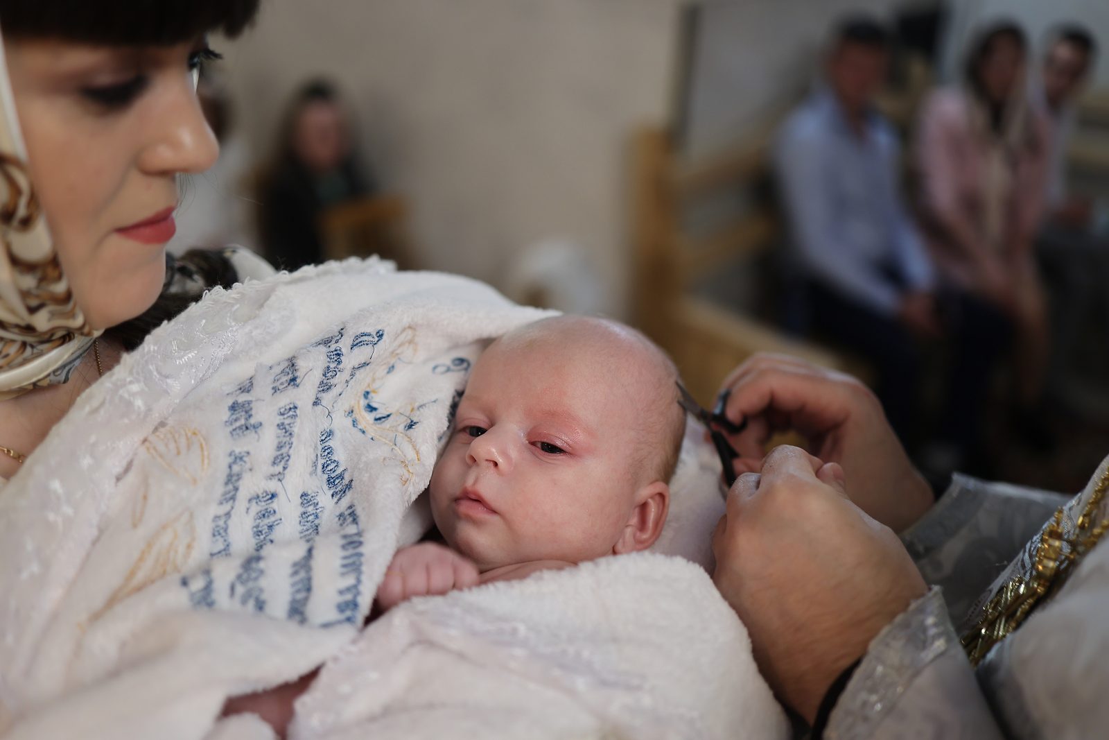 Priest touching an infant’s head during baptism