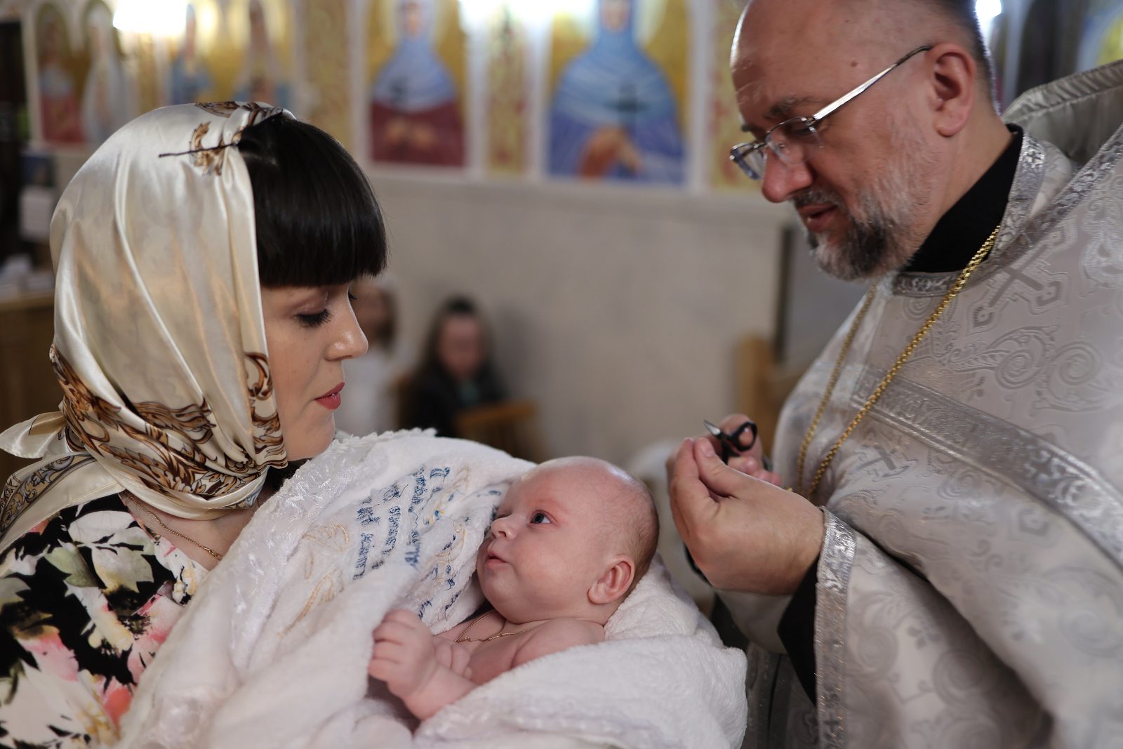 Priest performing a rite over an infant held by a woman