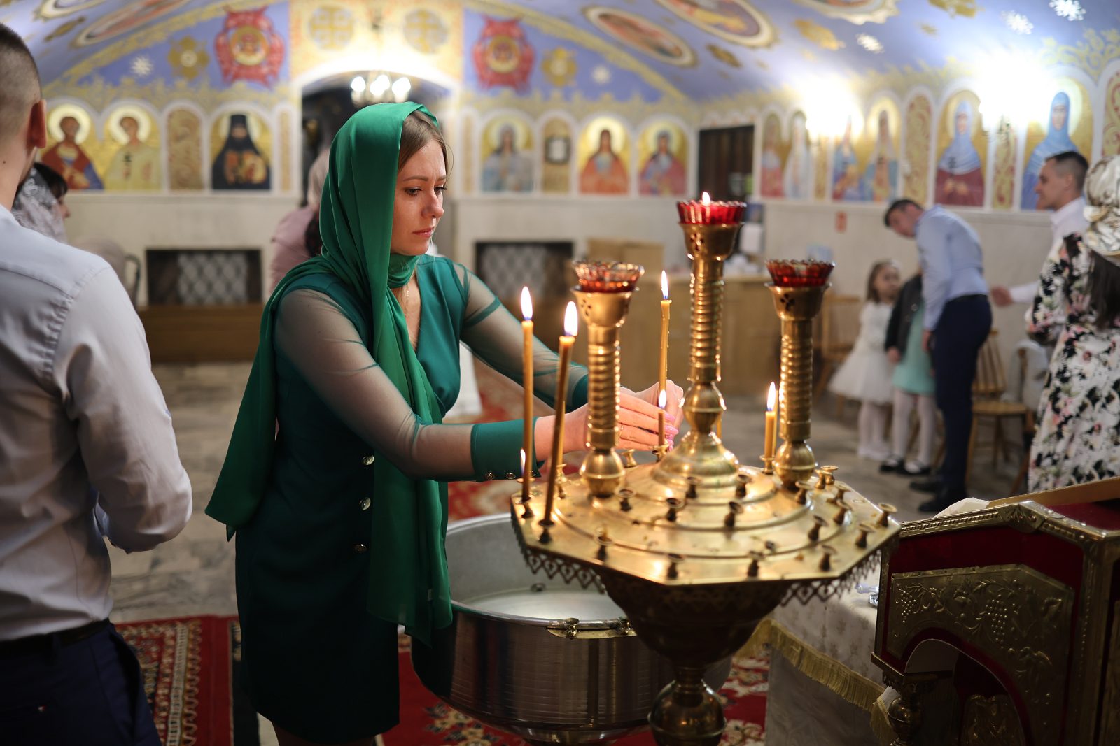 Woman lighting a candle at a candle stand