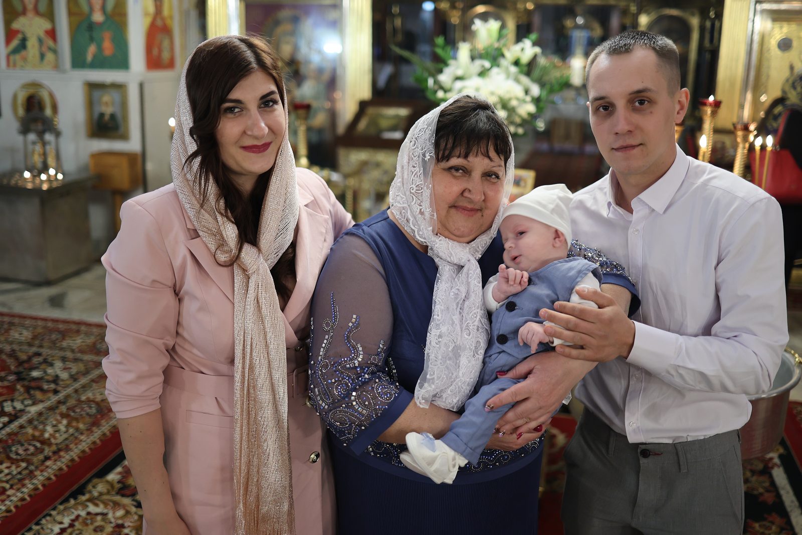 Three people posing with an infant in church
