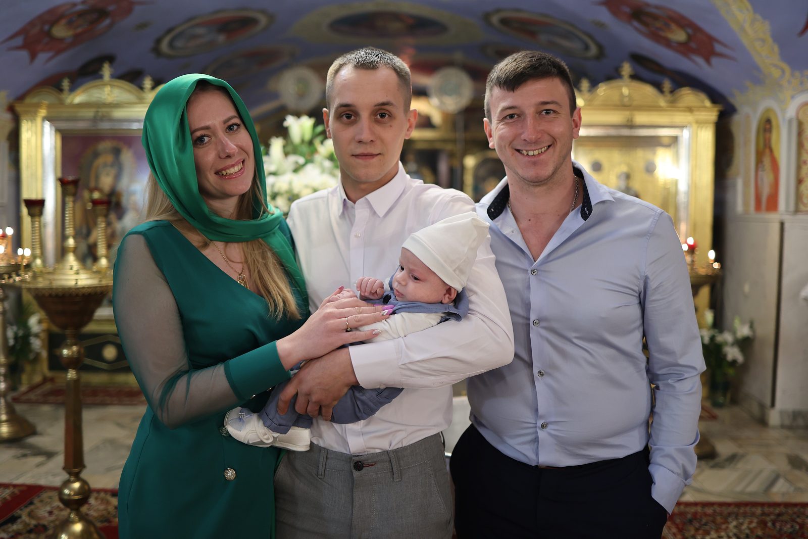 Three people posing with an infant before the iconostasis