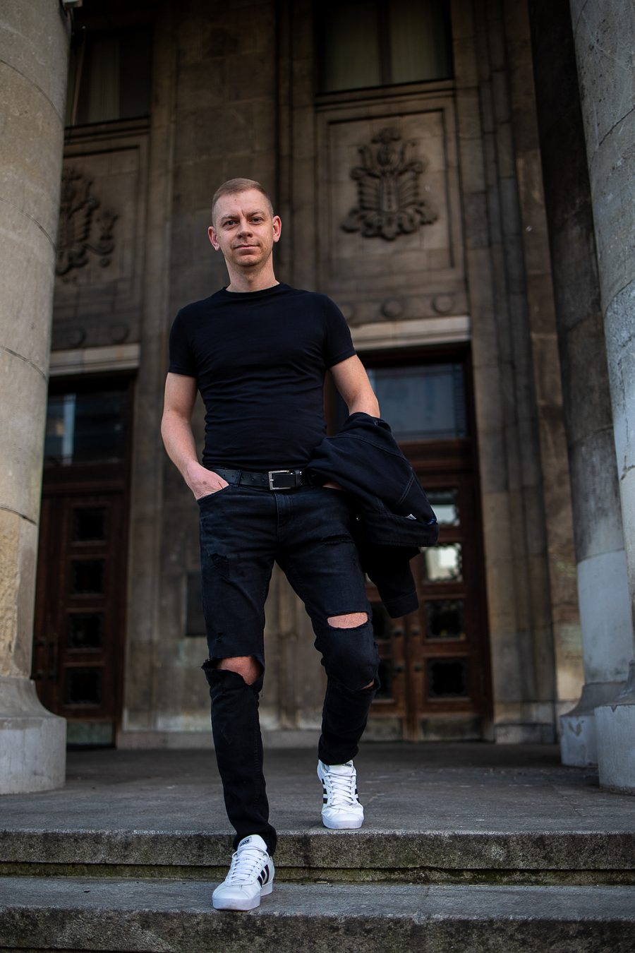 Mężczyzna w czarnym T-shircie wychodzi z budynku z kolumnami