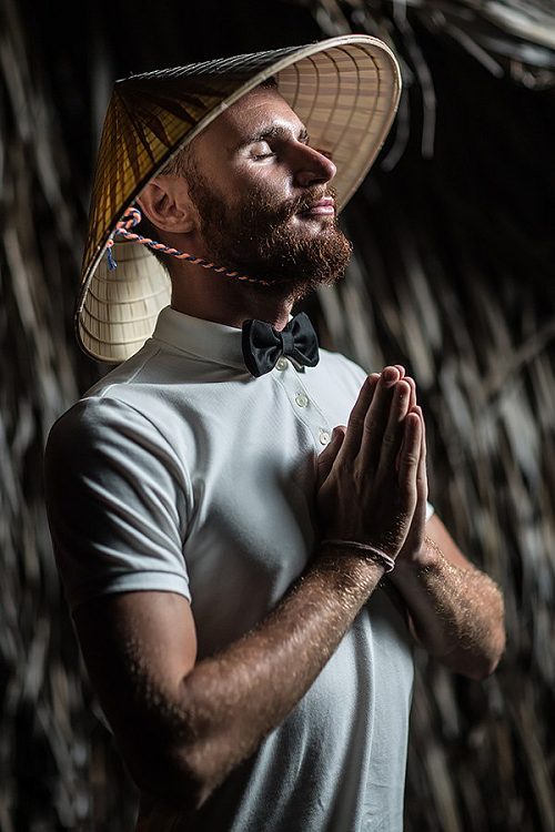 Man in a straw hat with hands folded before his face