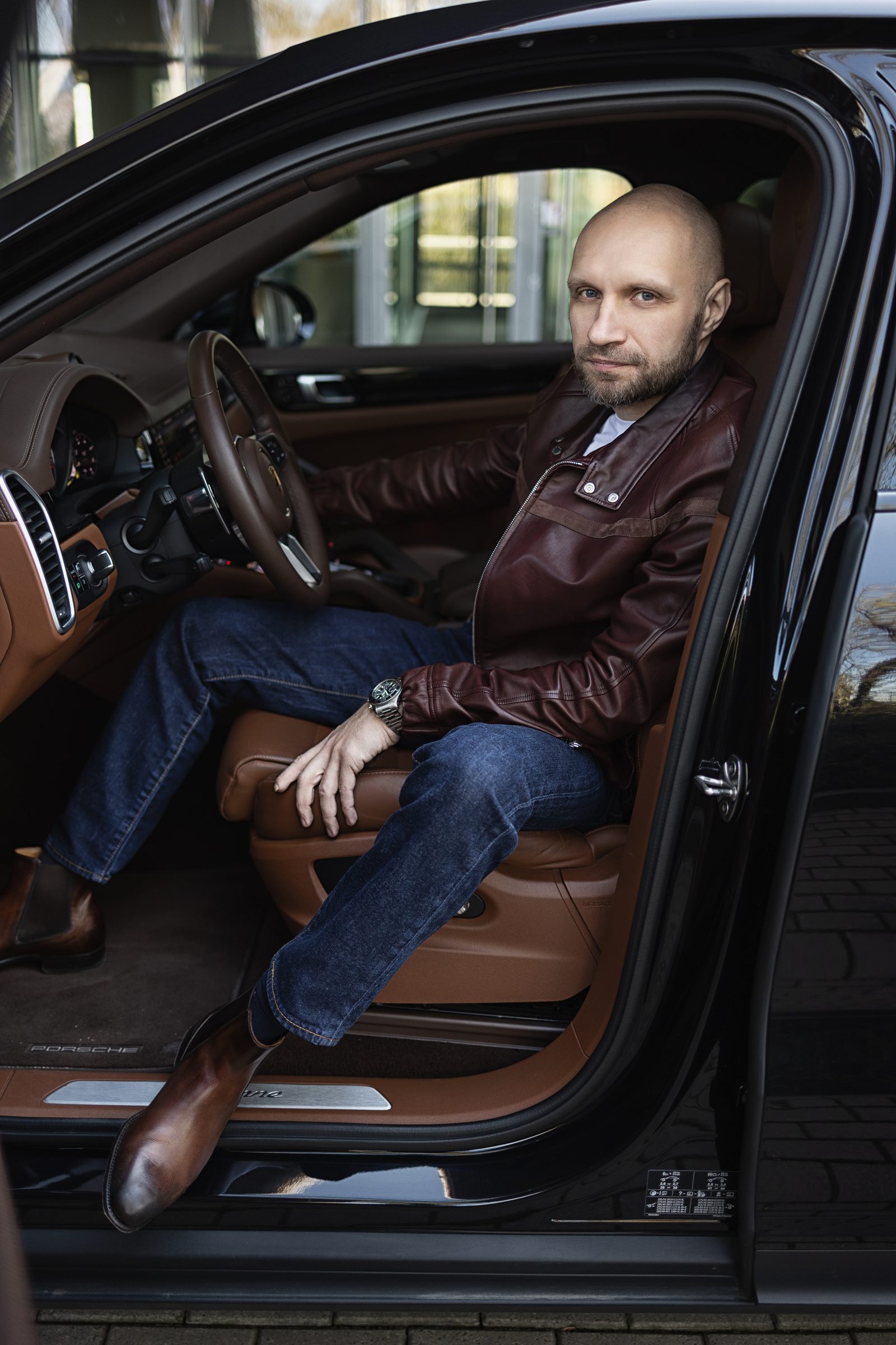 Мужской портрет за рулём чёрного Porsche Cayenne во время автомобильной фотосессии