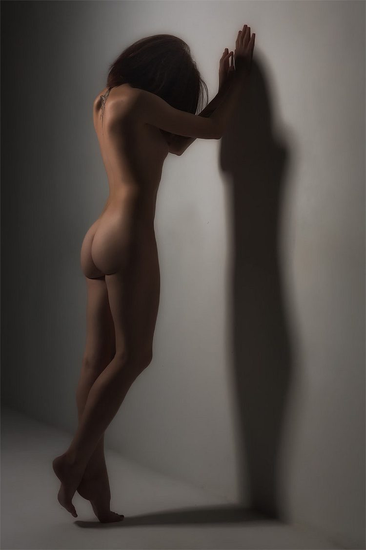 Silhouette of a woman against a light wall with a shadow