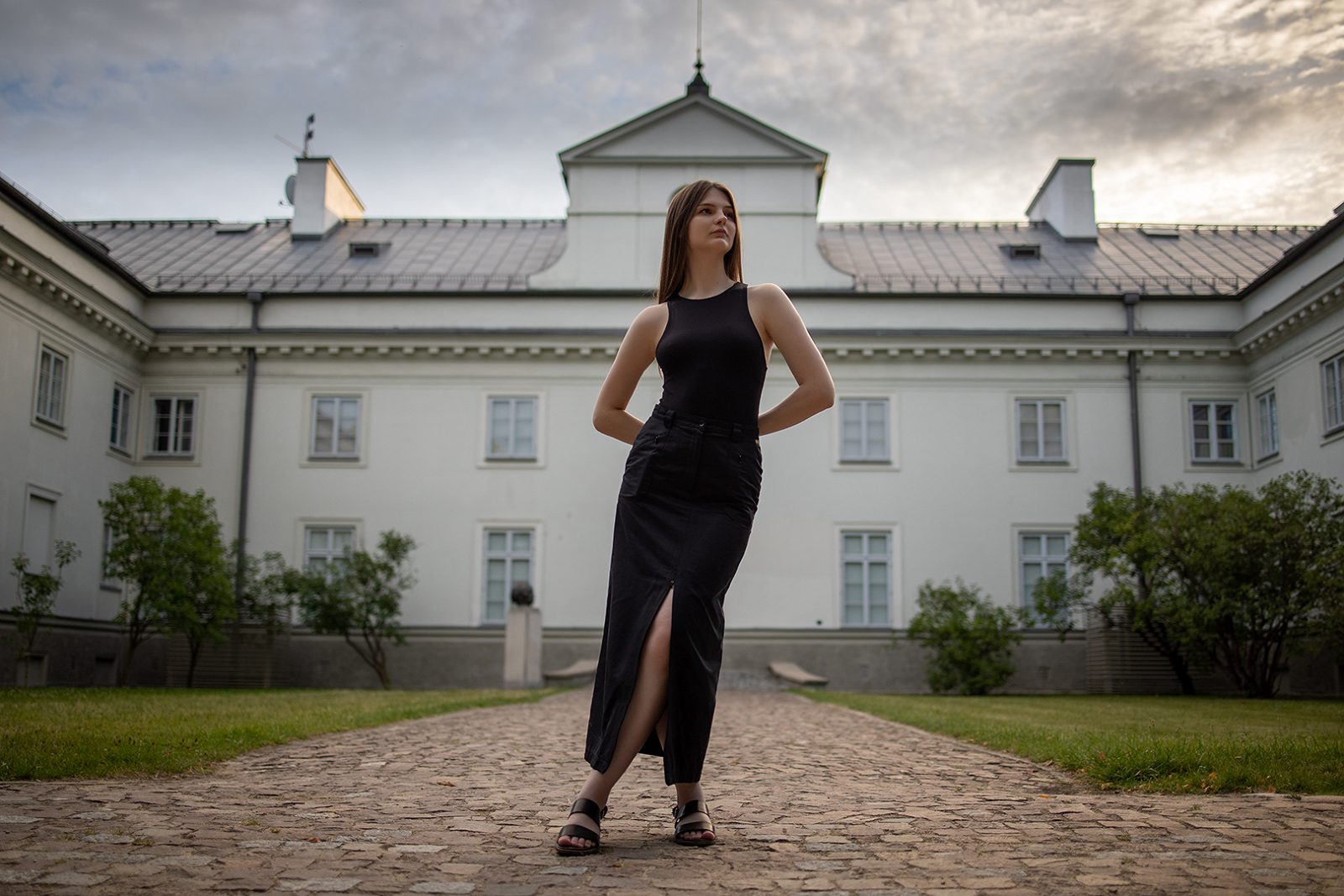 Kobieta w czarnej sukience przed jasną rezydencją