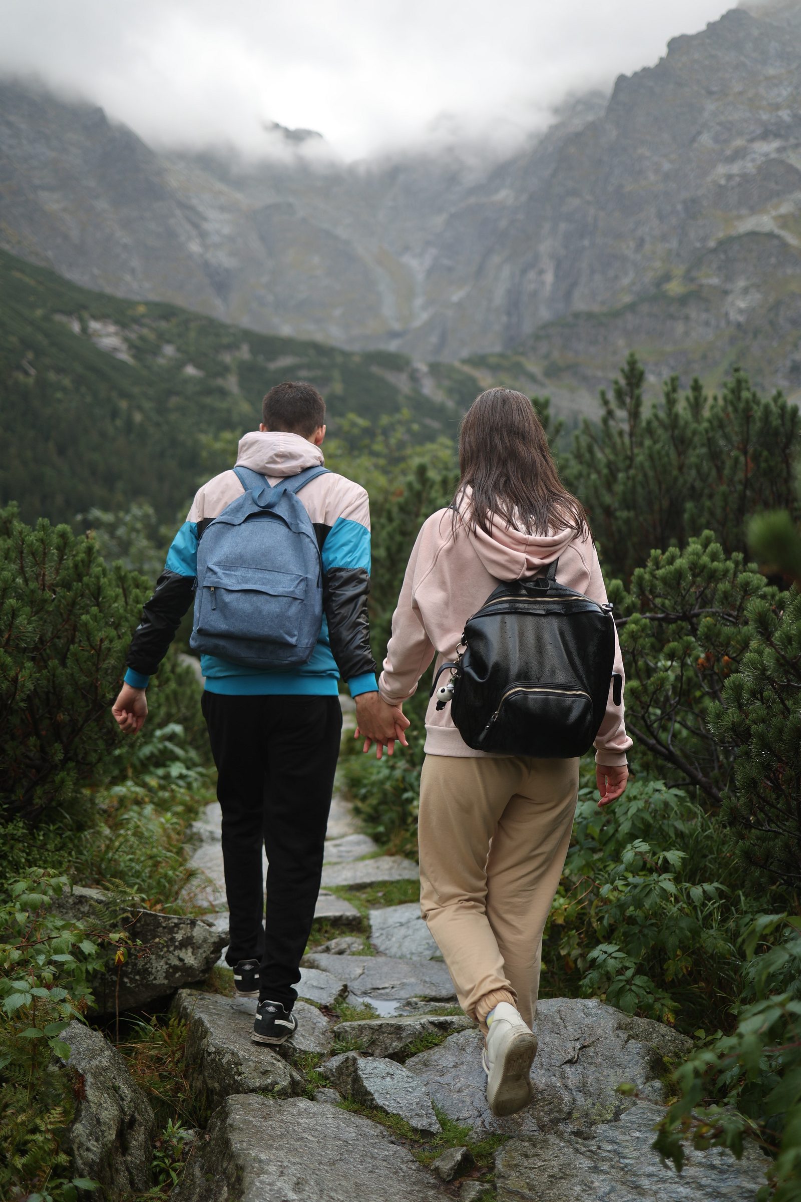 Couple with backpacks walking on a rocky mountain path