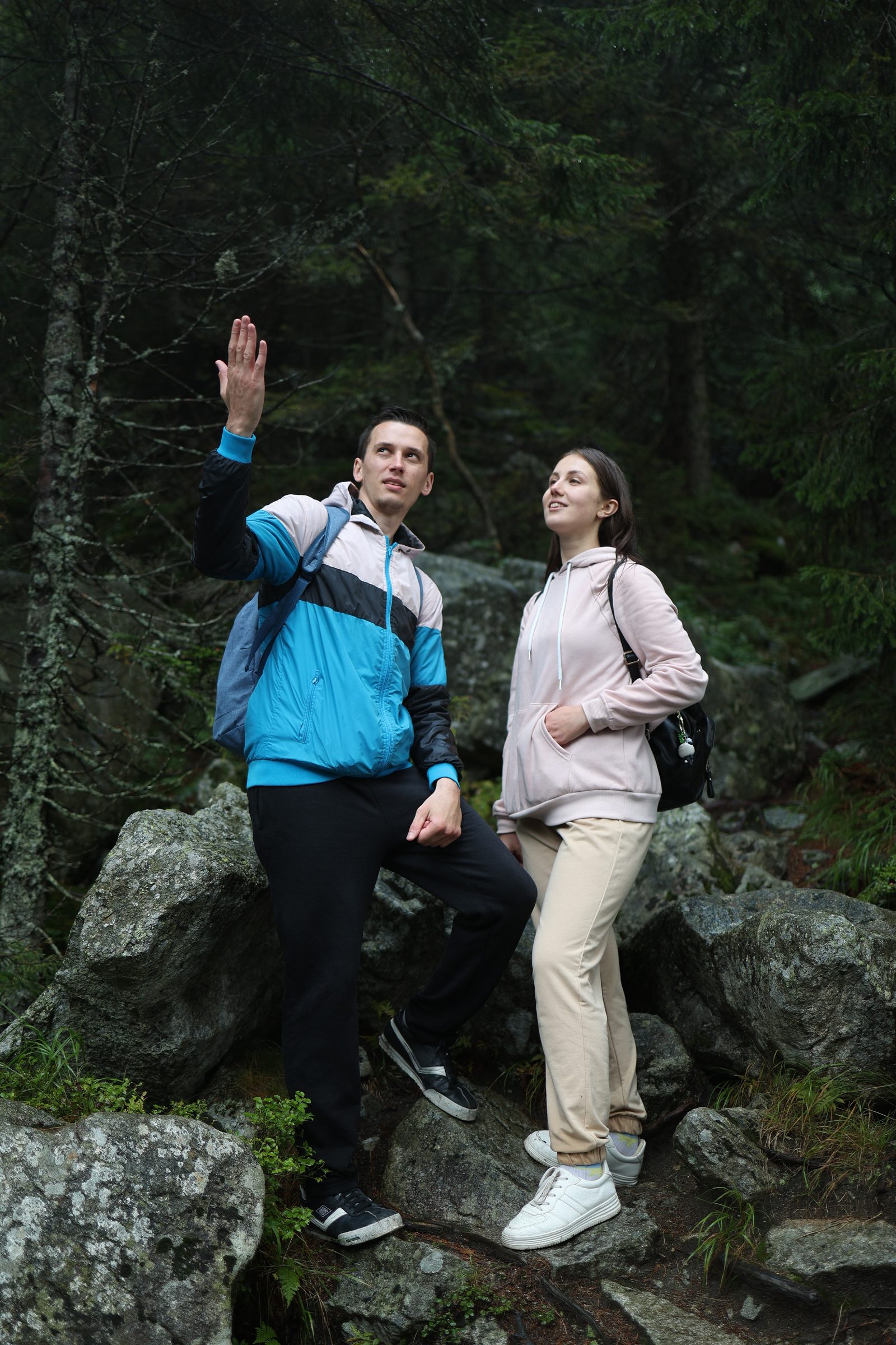 Man and woman standing among boulders in a forest