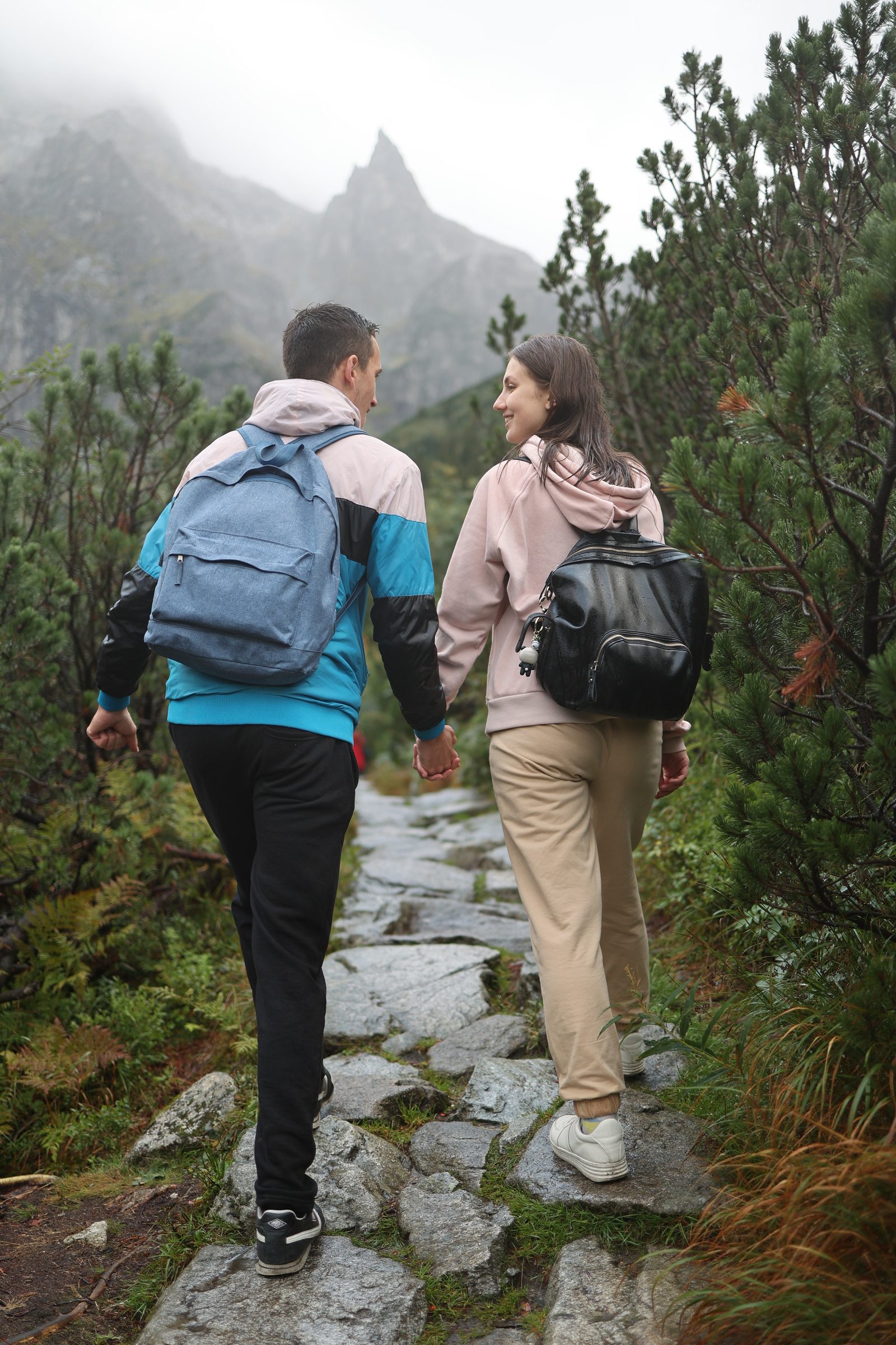 Couple with backpacks walking toward misty mountains