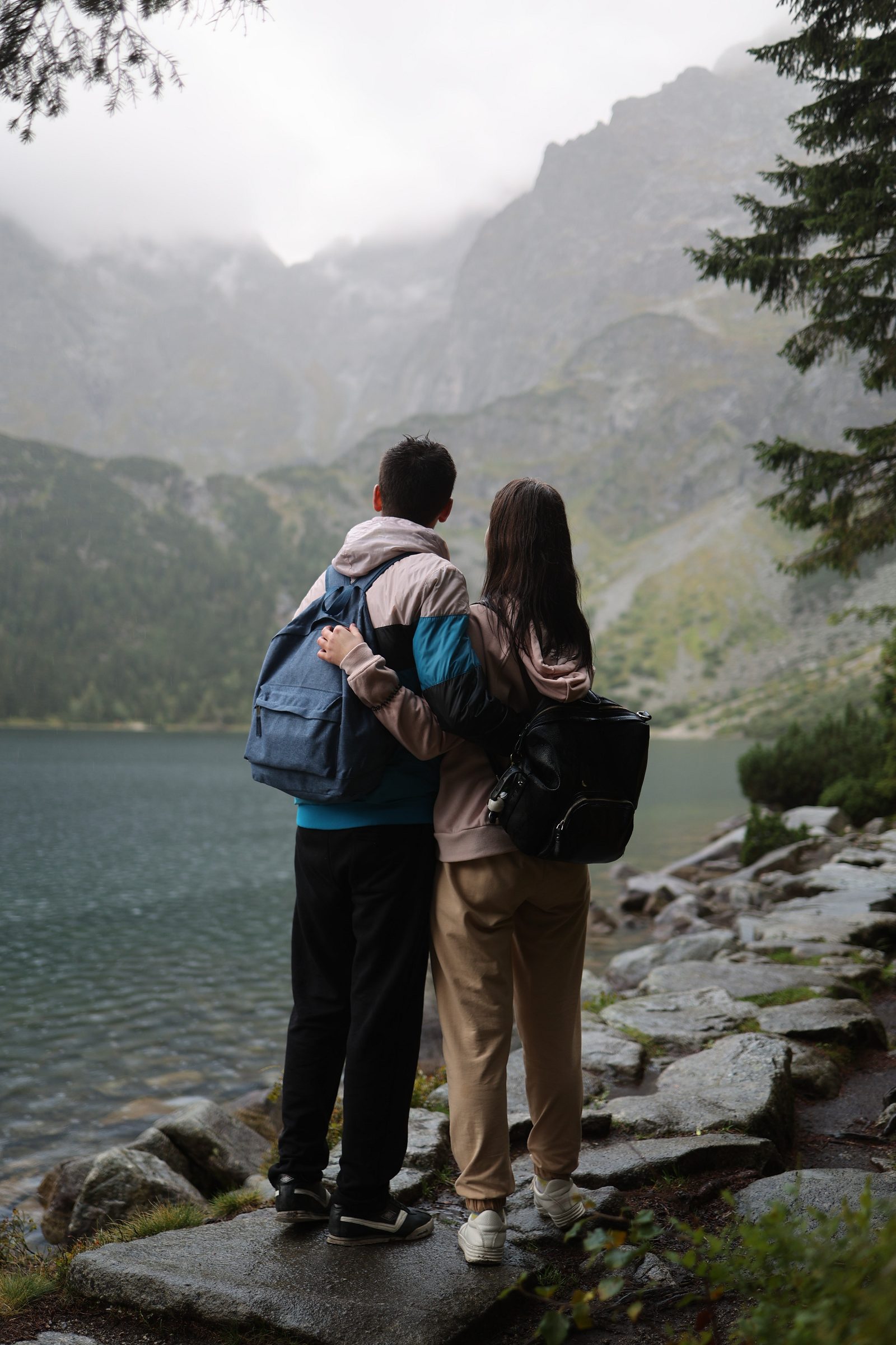 Couple with backpacks looking at a mountain lake