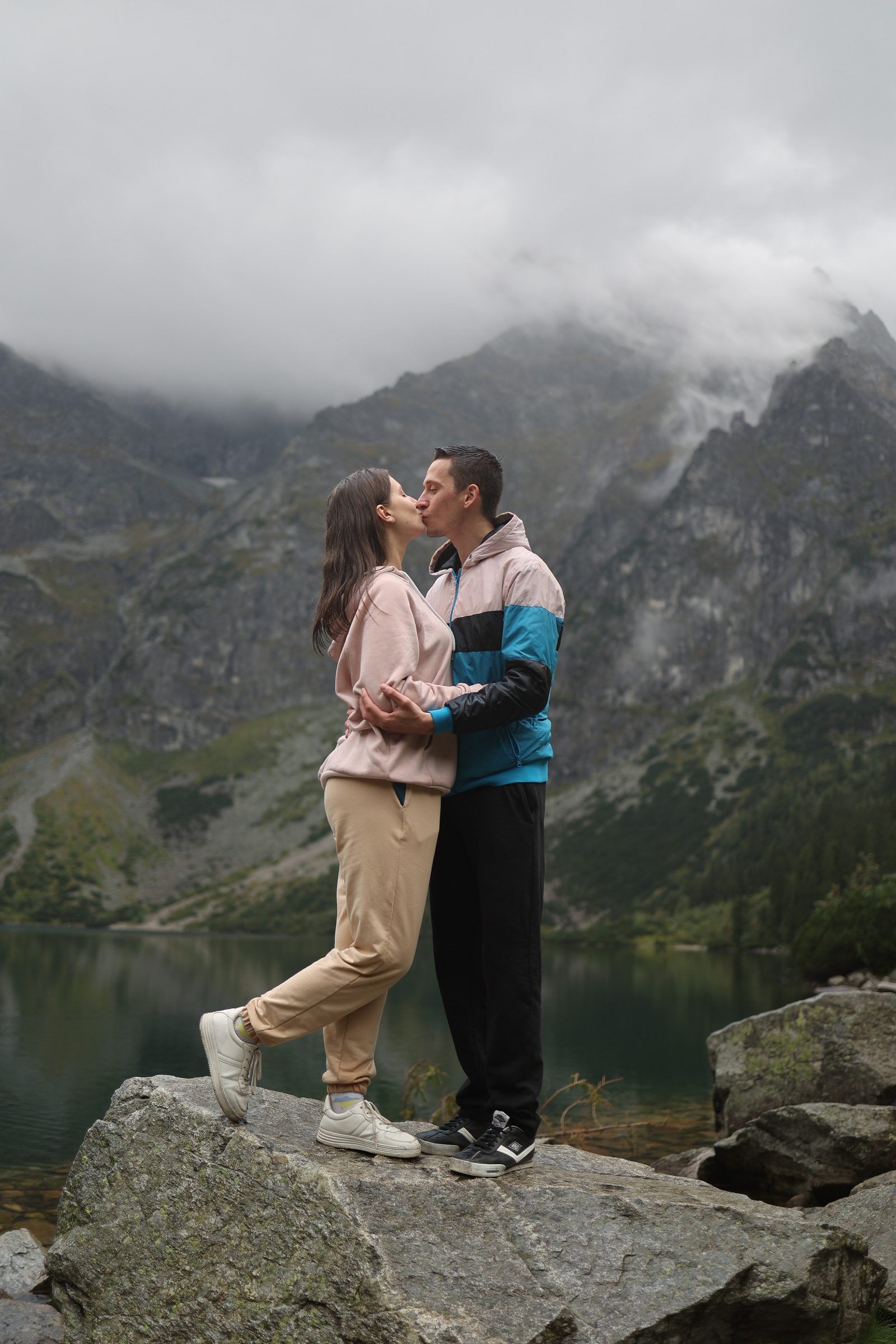 Couple kissing on a rock by a mountain lake