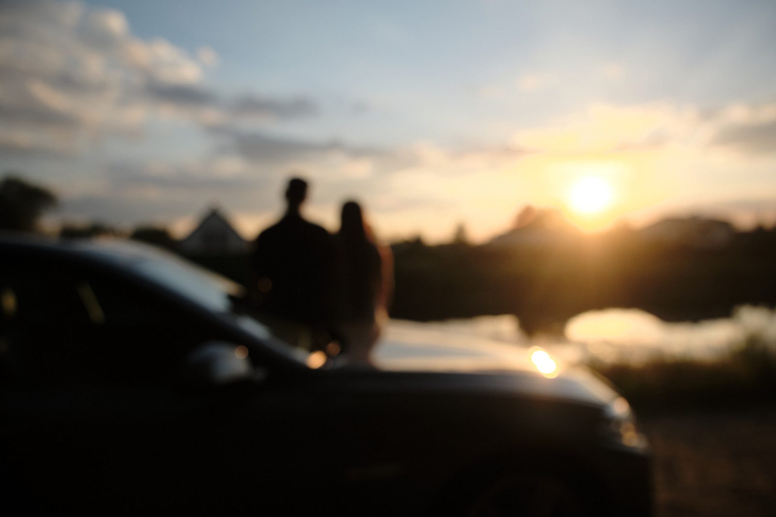 Couple beside a car by the water in the evening light