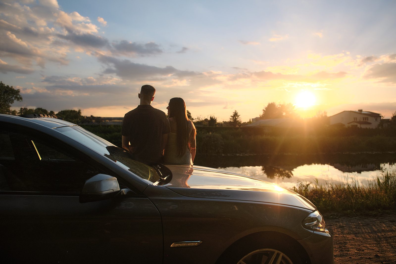 Blurred silhouettes of a couple beside a car at sunset