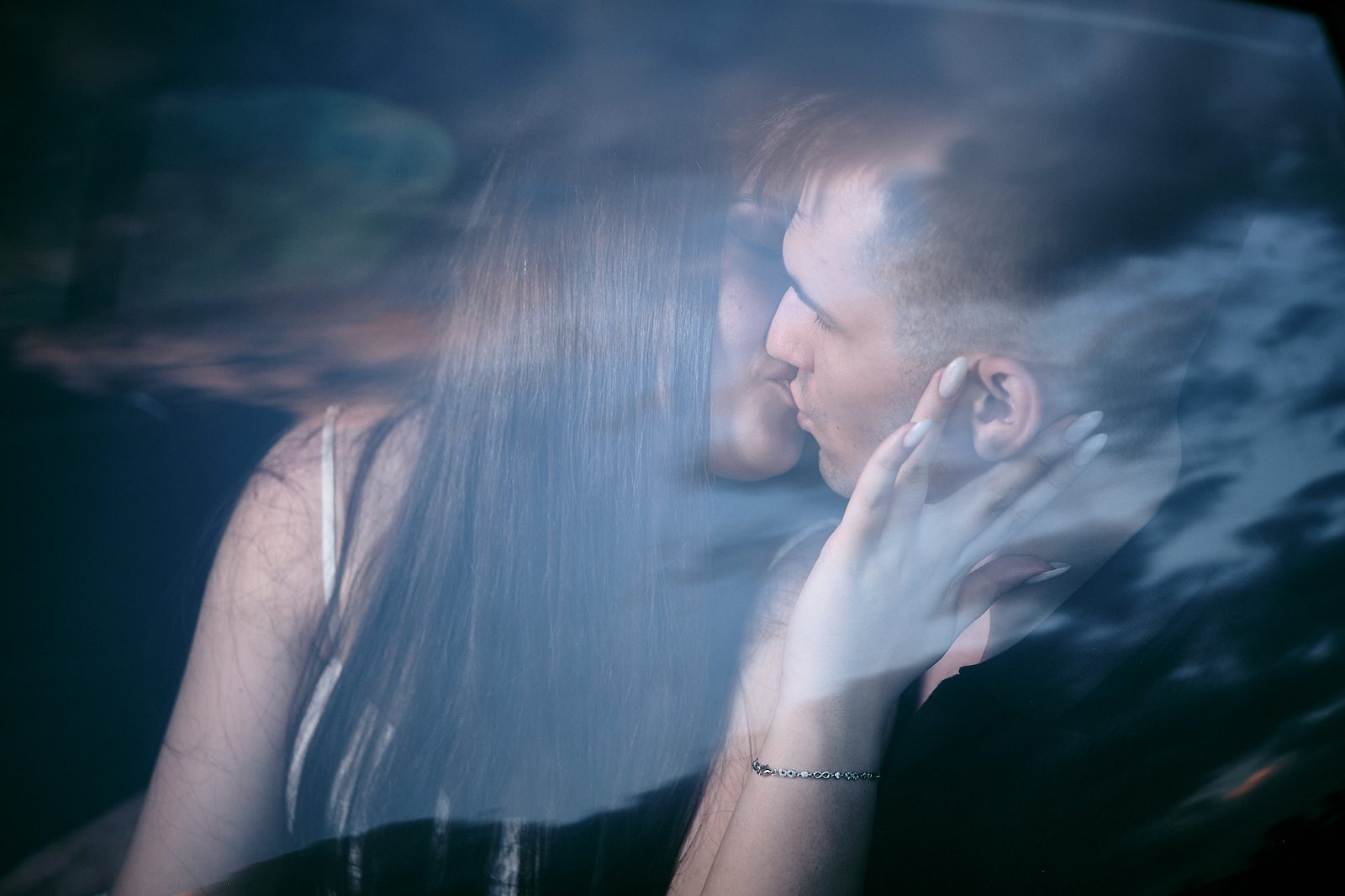 Close-up of a couple inside a car photographed through glass reflecting the sky