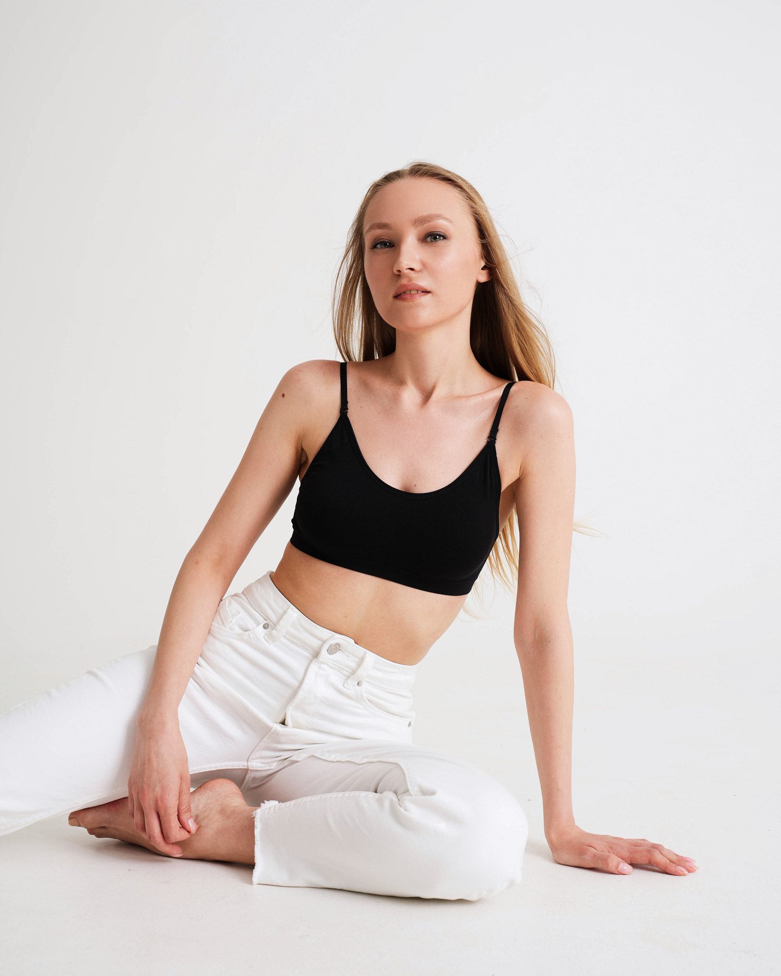 Woman in a black top sitting sideways on a white floor