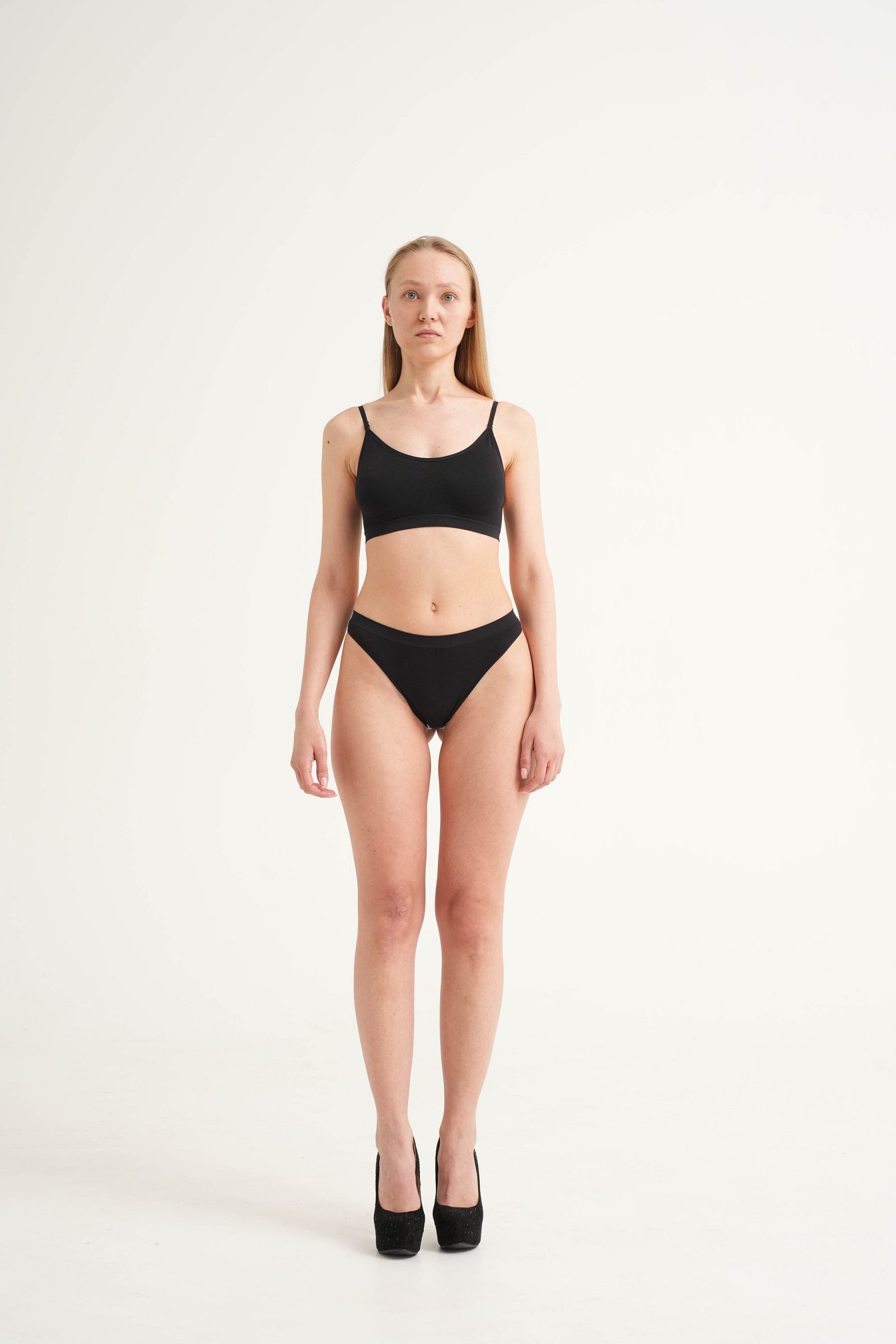 Woman in black underwear facing the camera against a white background