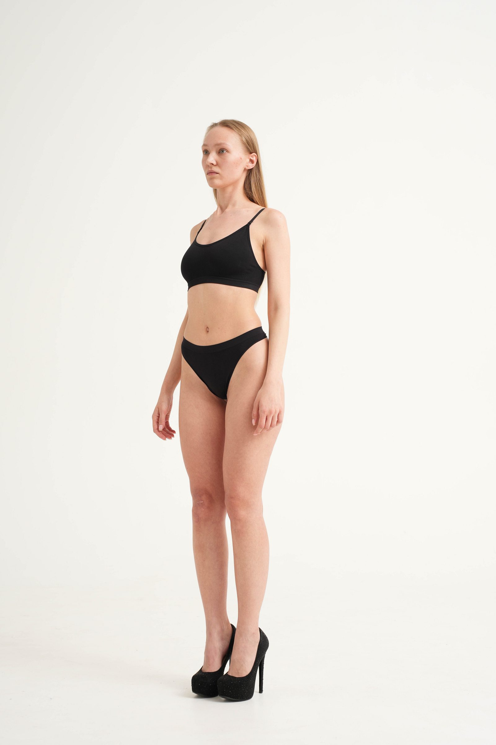 Woman in black underwear standing in a three-quarter pose
