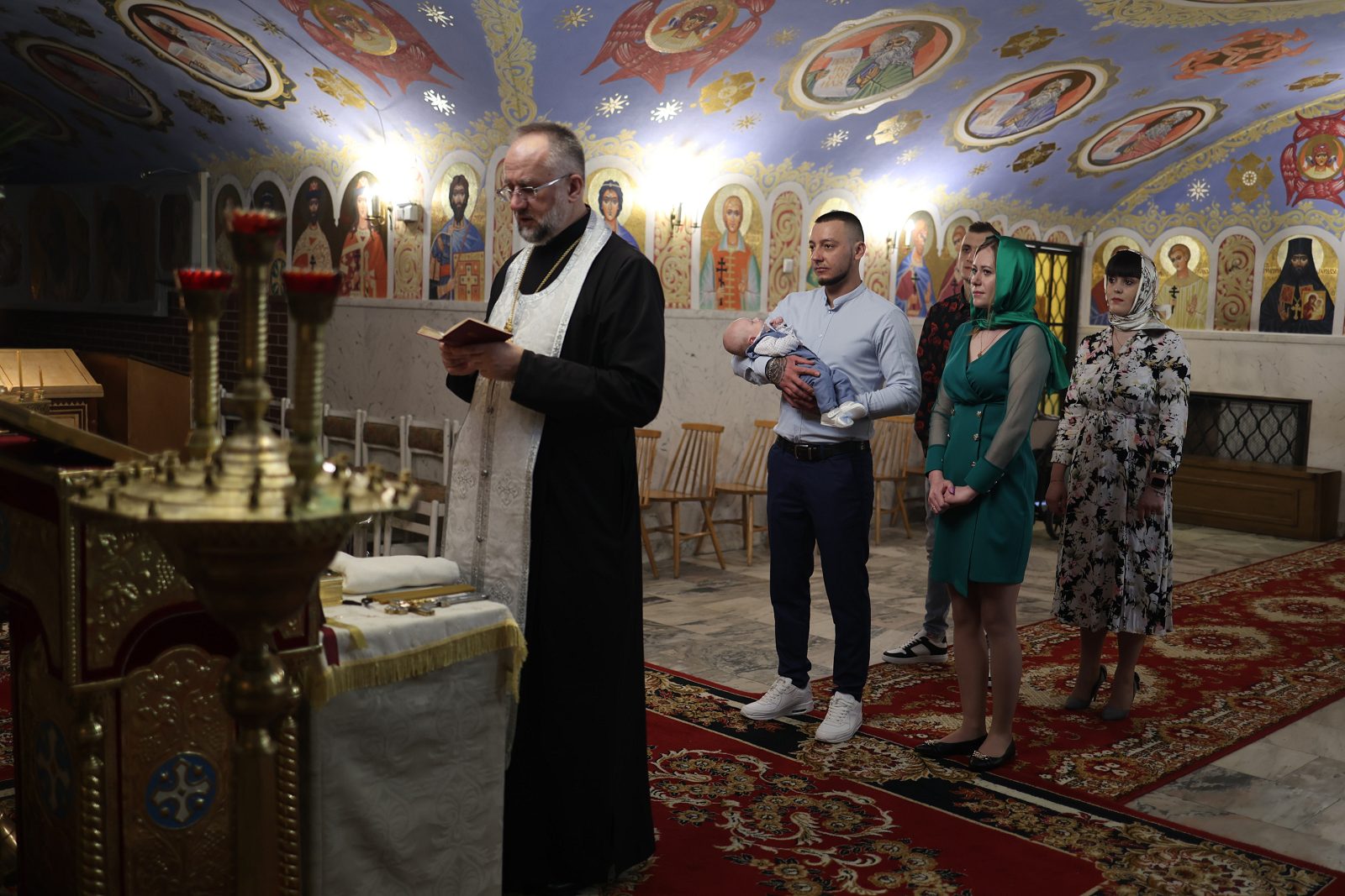 Священник читає молитву перед родиною під час хрещення