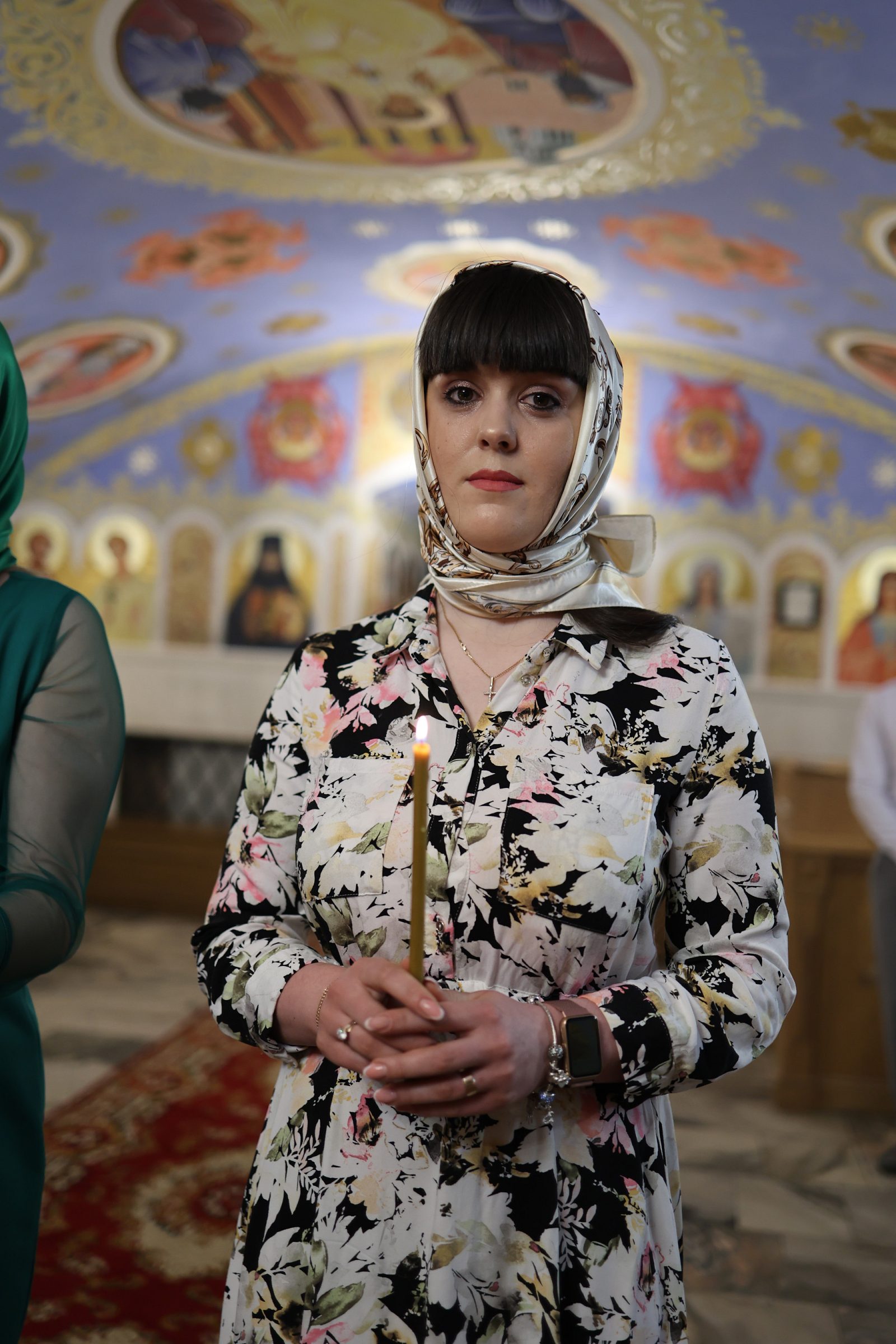 Жінка із запаленою свічкою в храмі під час хрещення