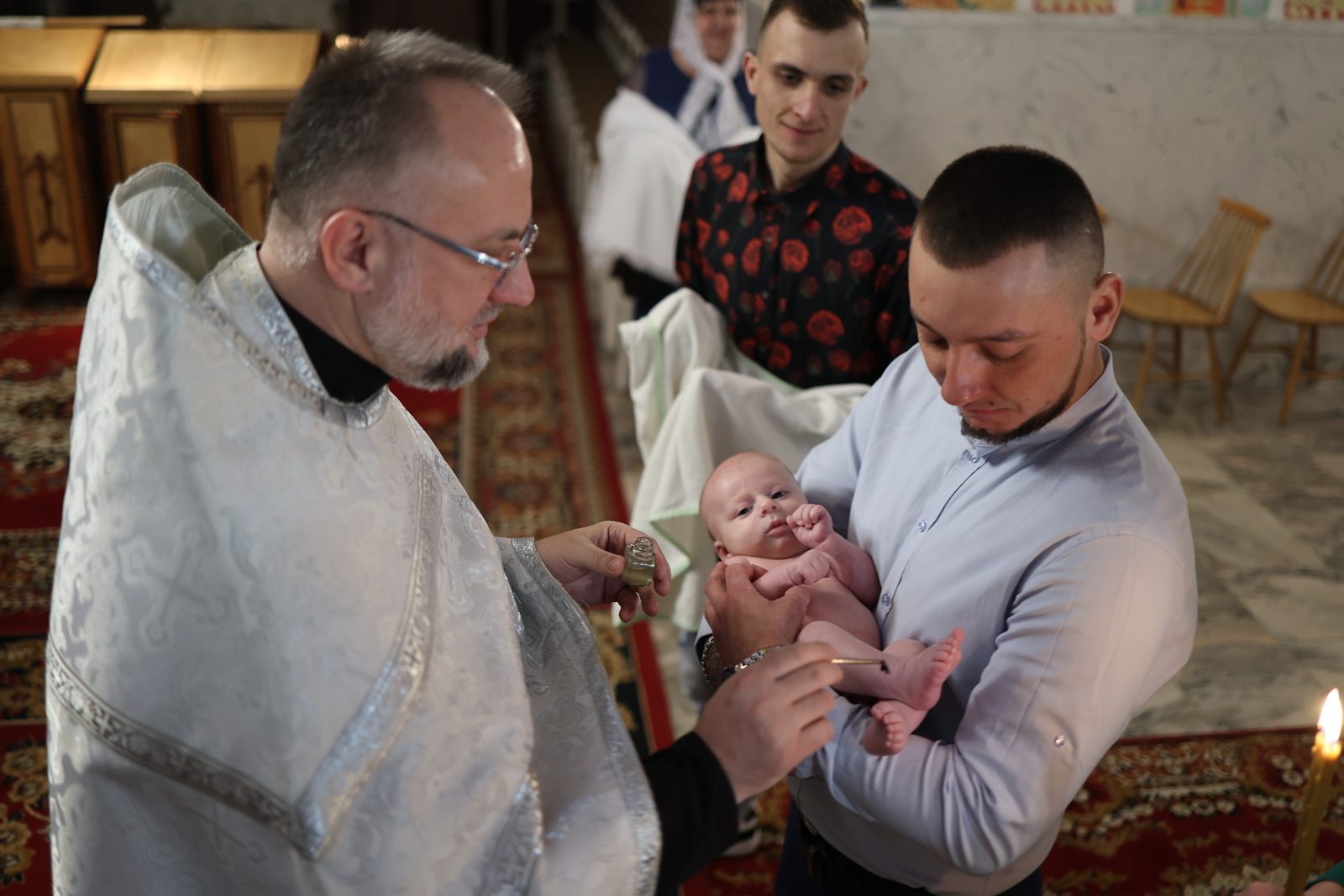 Священник торкається немовляти під час таїнства хрещення