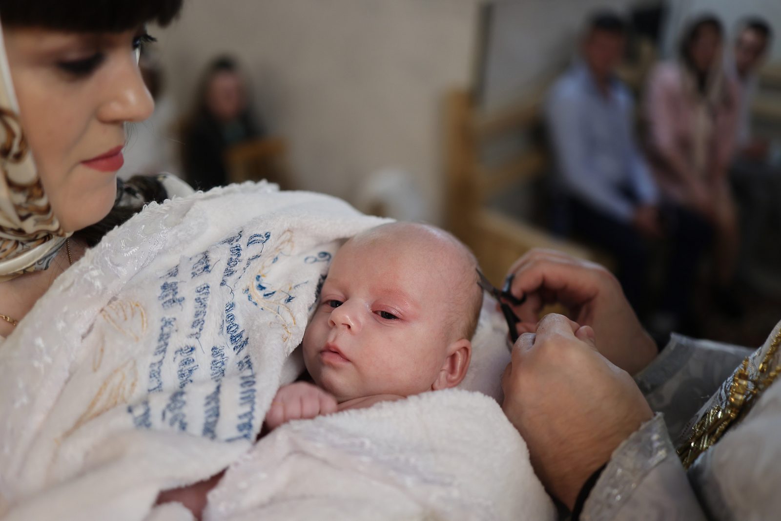 Священник торкається голови немовляти під час хрещення