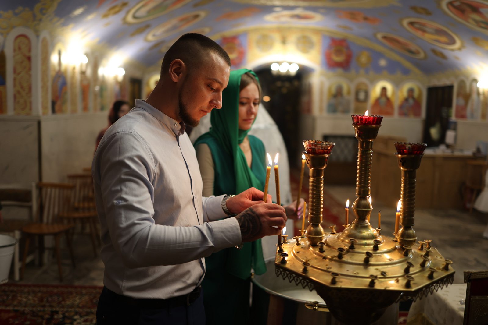 Чоловік запалює свічку в храмі