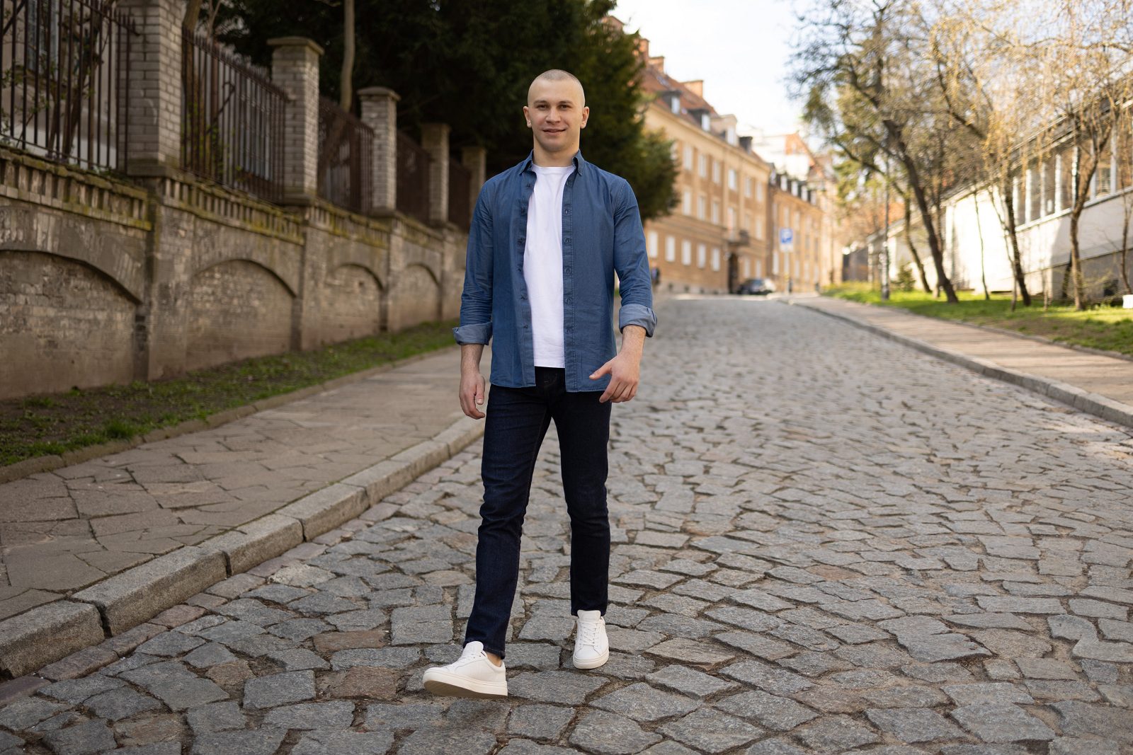 Mężczyzna w niebieskiej koszuli stoi na brukowanej ulicy