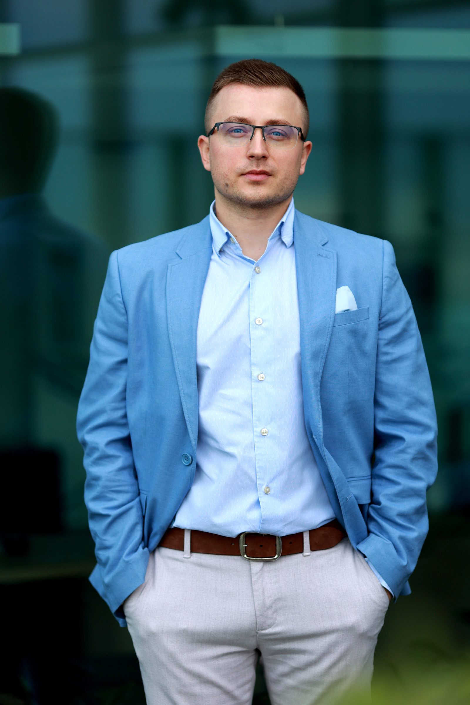 Man in a light blue blazer before a glass facade