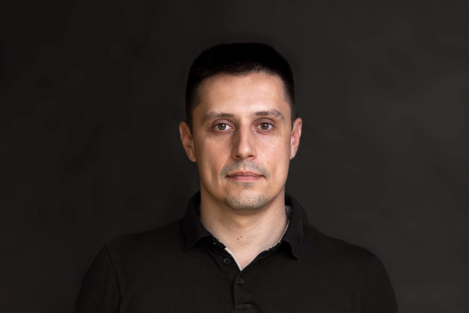 Studio portrait of a man in a black polo shirt
