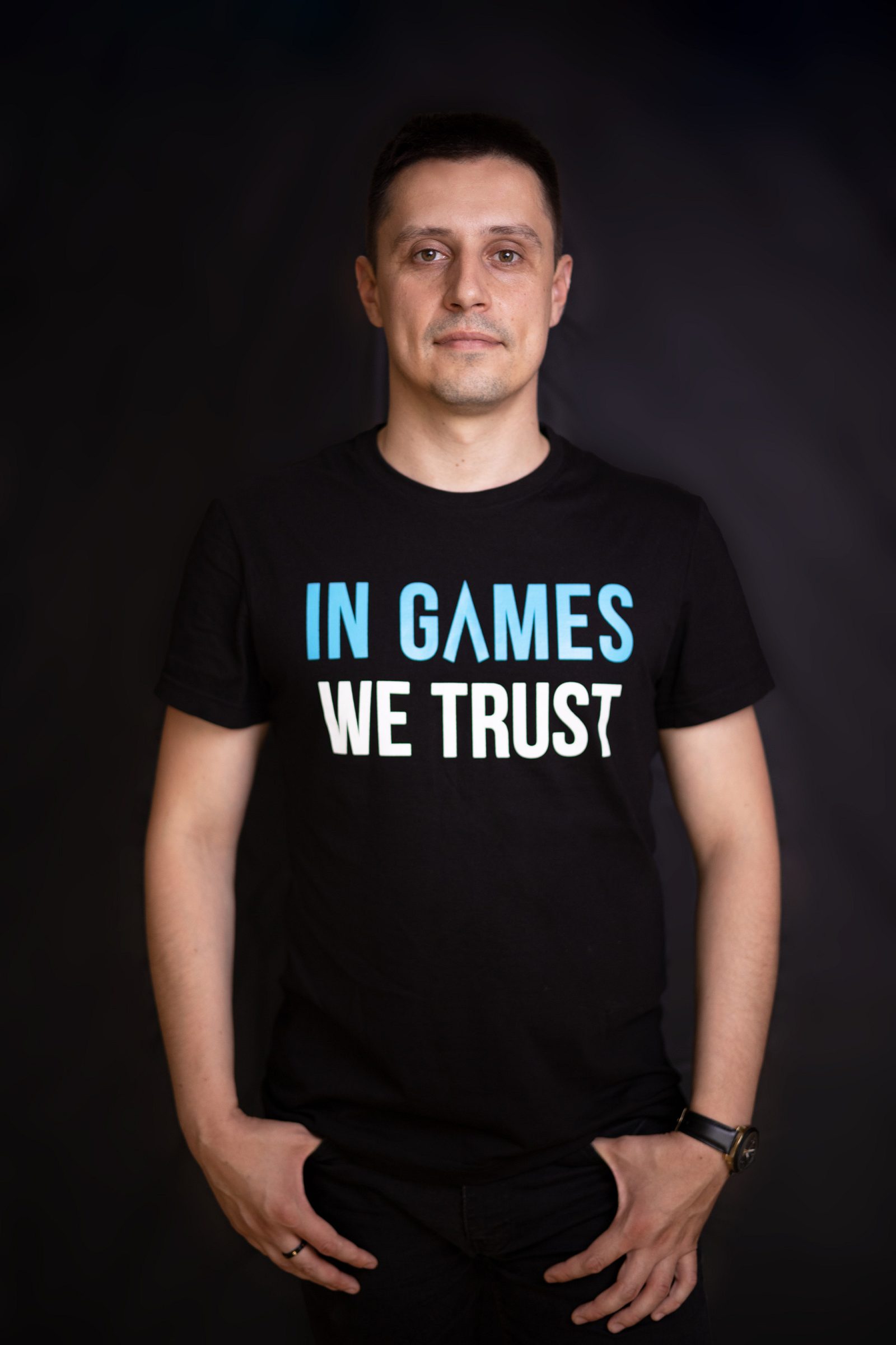 Man in a black T-shirt reading “IN GAMES WE TRUST”