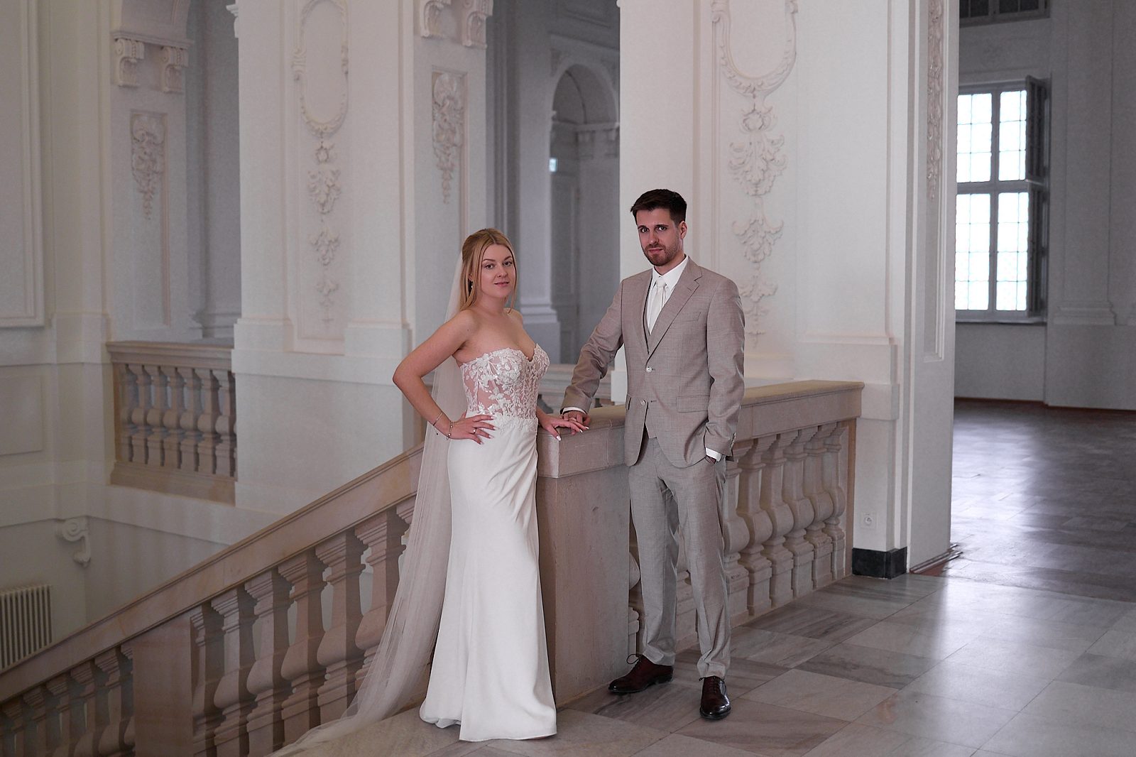 The groom dances with the bride in a bright gallery with vaulted ceilings and hanging lanterns.