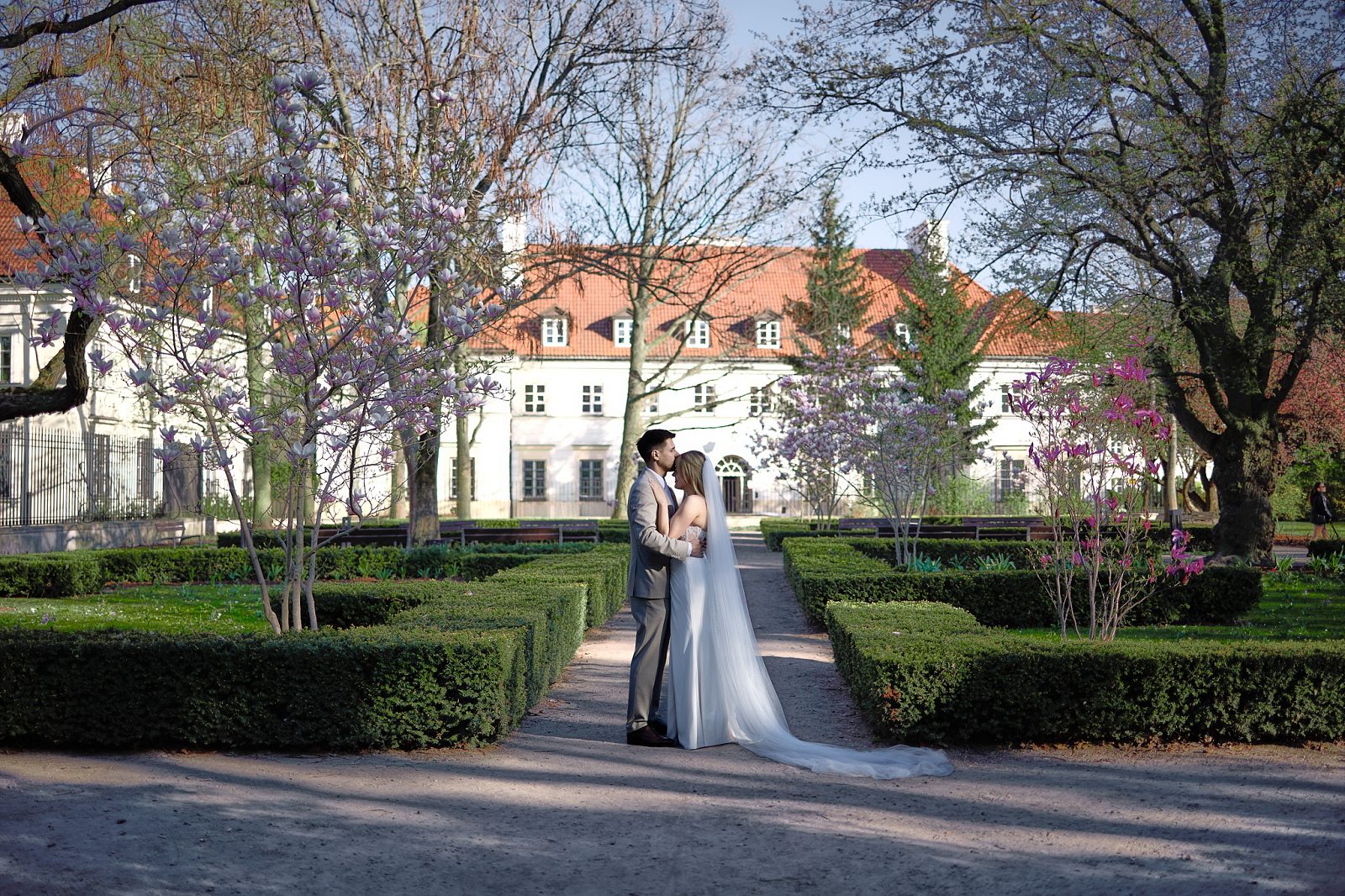 The newlyweds kiss on the lawn in front of the palace’s grand facade.