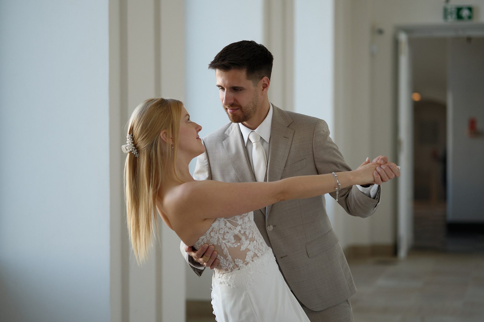 The newlyweds dance indoors while holding hands.