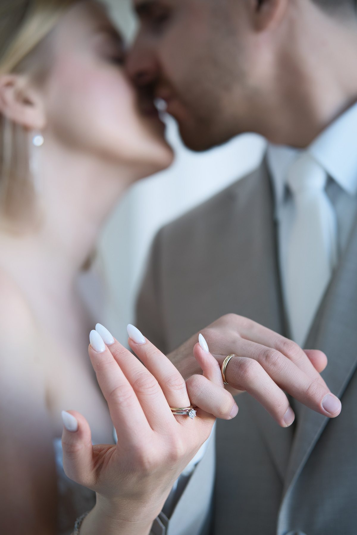 Close-up of the newlyweds kissing, with wedding rings visible on their hands.