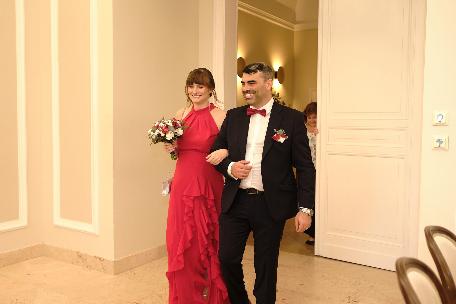 Nowożeńcy idą pod rękę przez salę ceremonii.