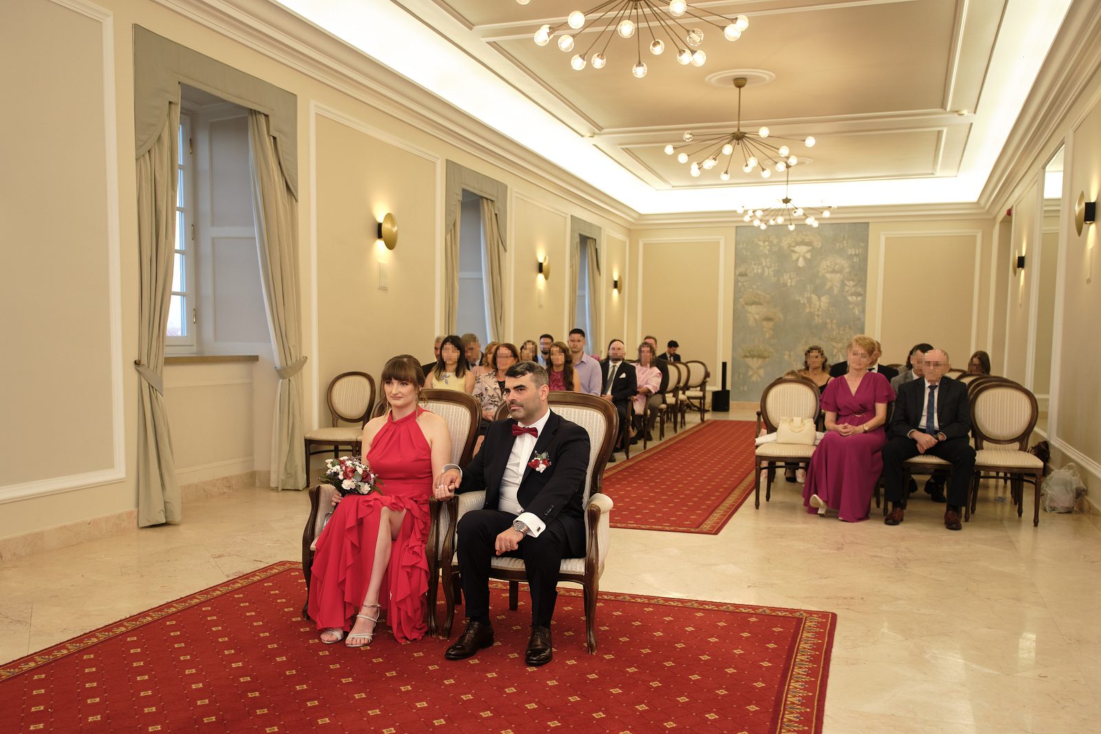 Szeroki kadr sali ceremonii z gośćmi i nowożeńcami.