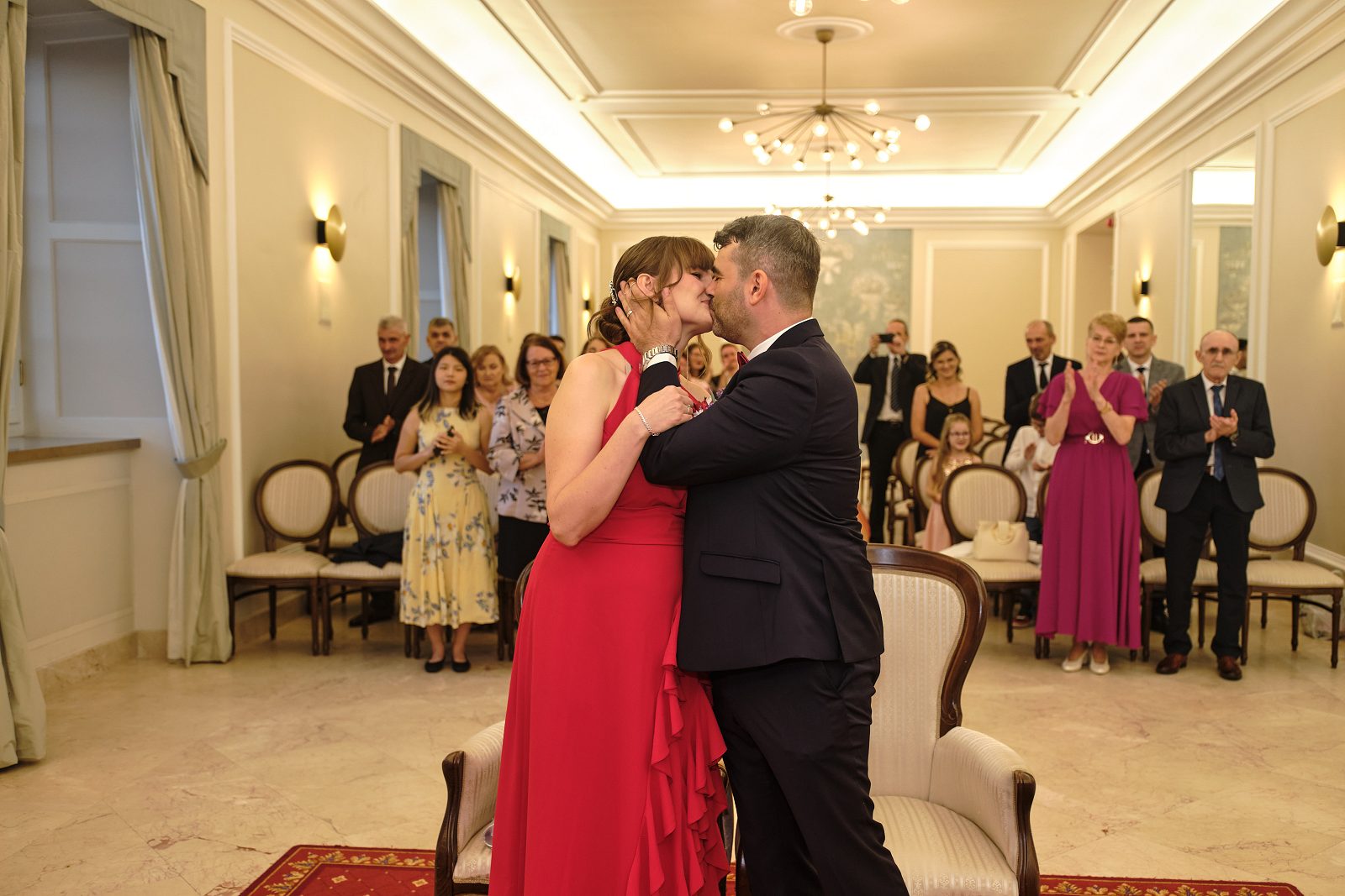 Nowożeńcy całują się przy aplauzie gości.