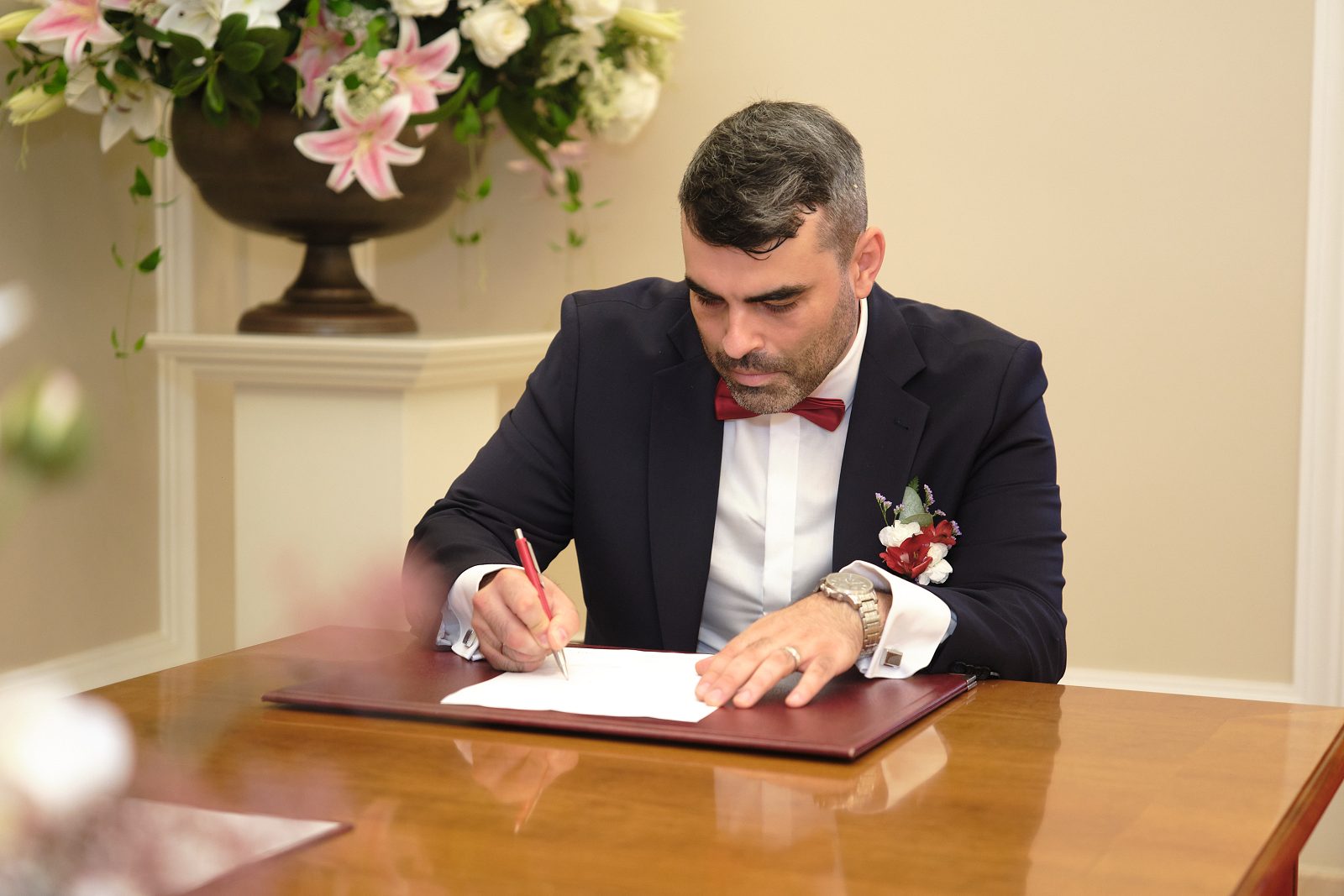 Pan młody podpisuje dokument podczas ceremonii.