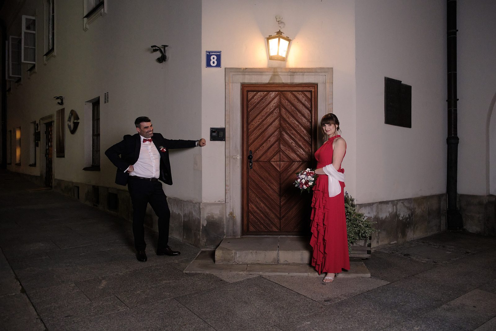Pan młody i panna młoda pozują po obu stronach wejścia.